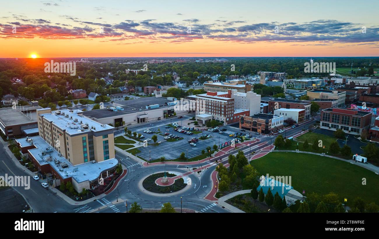 Muncie, IN sun setting on horizon with aerial of downtown buildings and ...