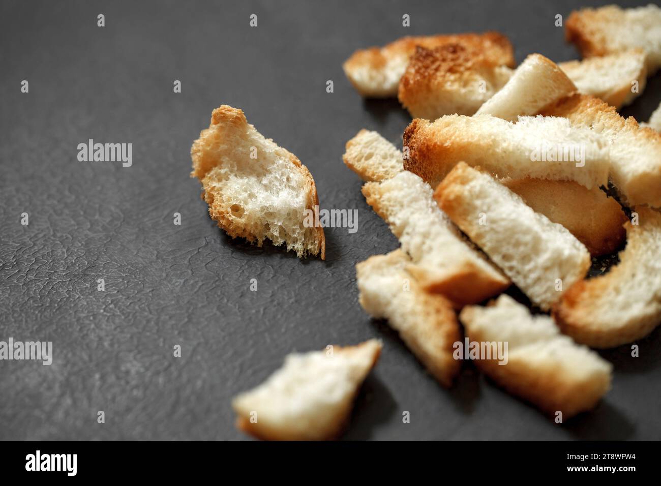 Crackers, dried baked bread pieces on dark background, selective focus. Stock Photo