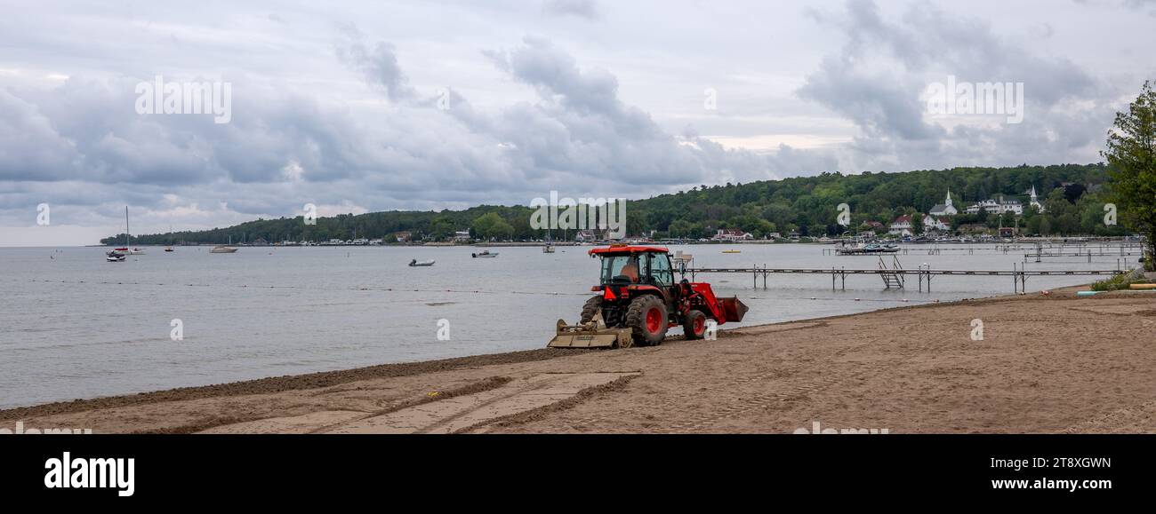 DOOR CO, WI – 14 AUG 2023: A tractor pulling a rotary tiller to maintain a beach at Ephraim, Wisconsin on the shore of the waters of the Green Bay of Stock Photo