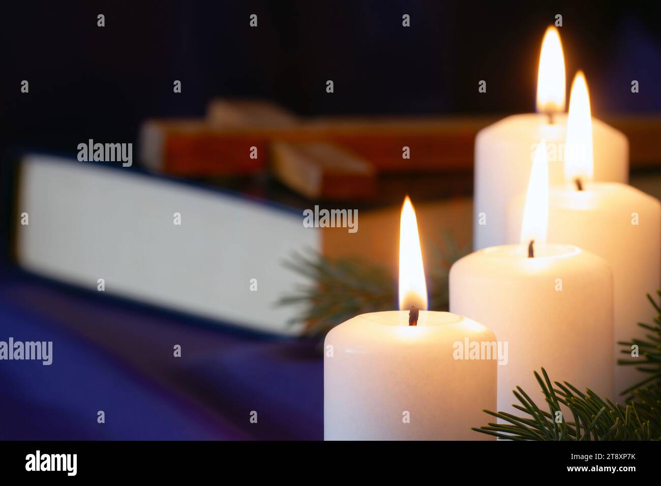 Four burning Advent candles with Bible and cross in background