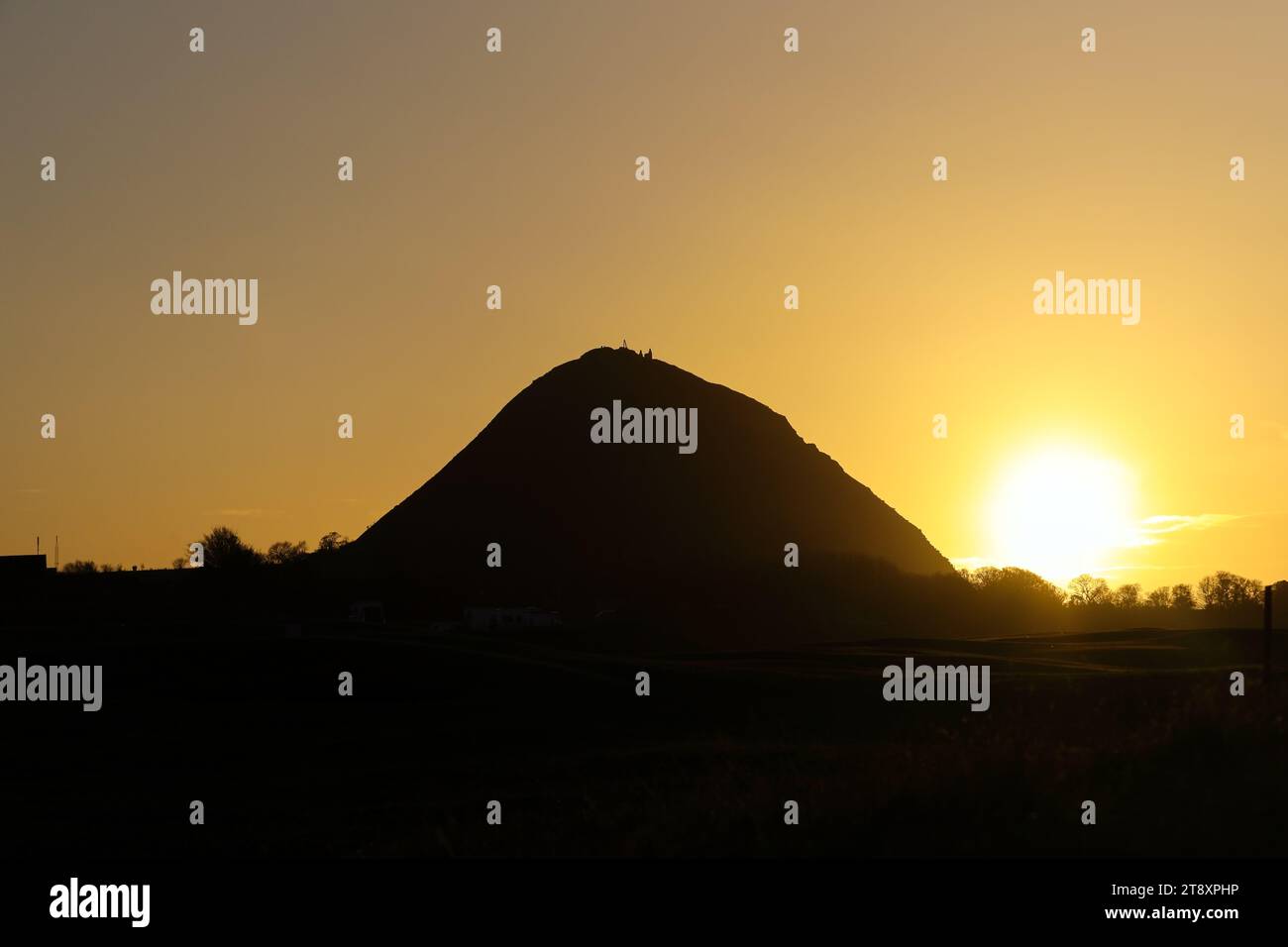 The sun setting behind the hill of North Berwick Law, North Berwick, East Lothian, Scotland, UK Stock Photo