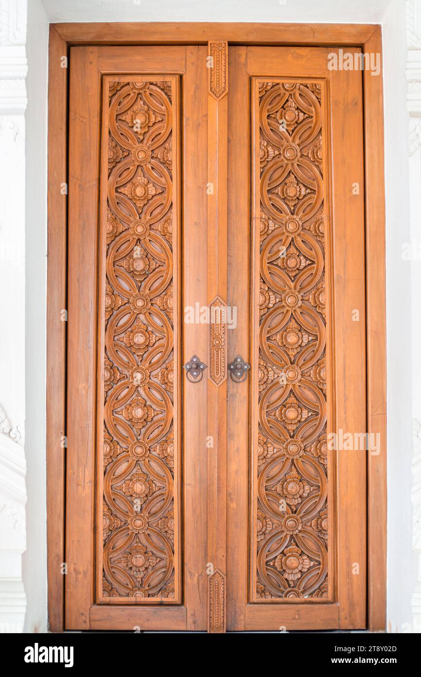 Wooden double-leaf carved door with beautiful ornaments and iron handles. Stock Photo
