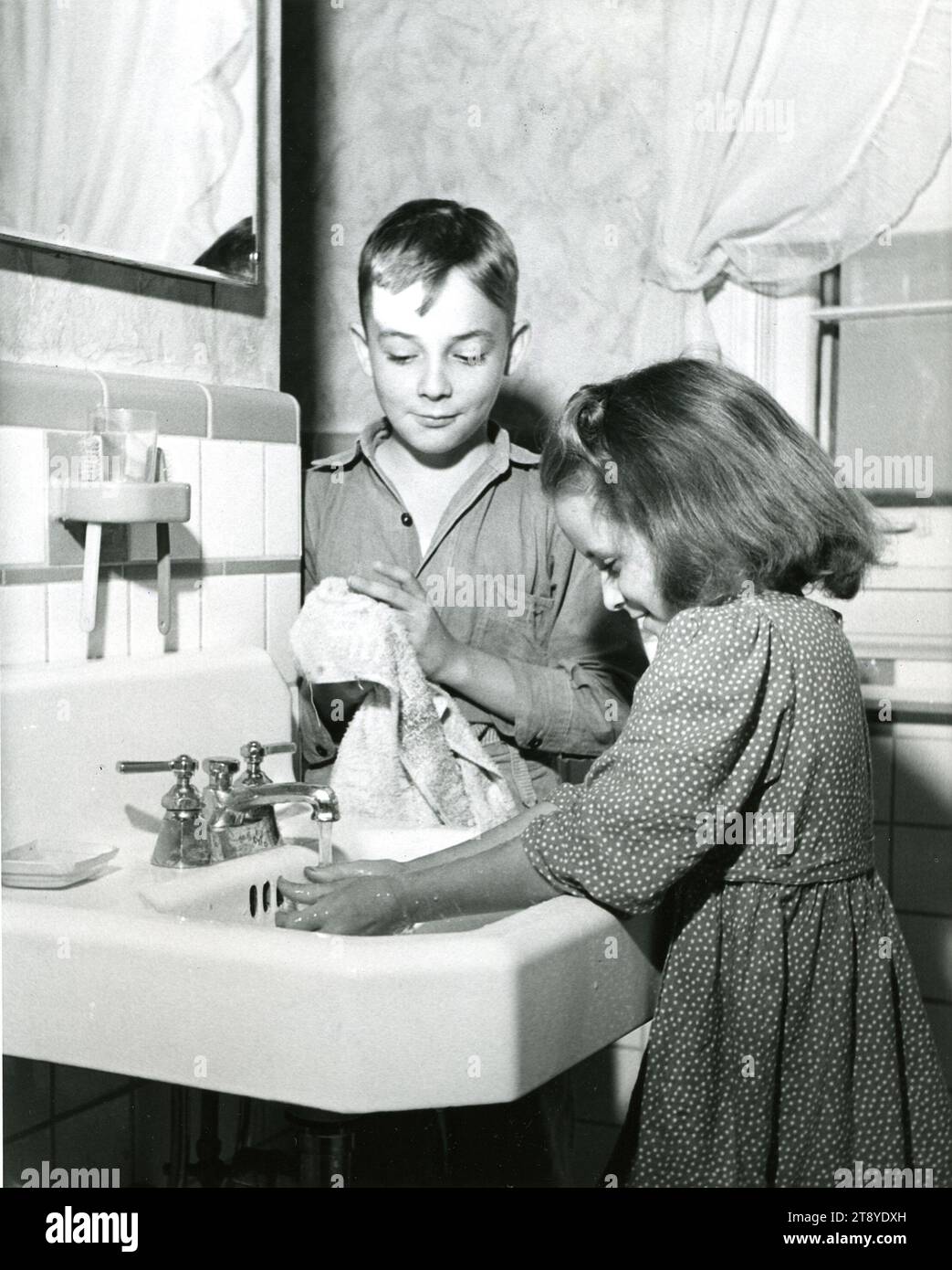 Tennessee, 1961 - Children in a farm house electrified under the Tennessee Valley Authority (TVA) program enjoy the advantages of indoor plumbing. Electricity, in addition to supplying water indoors and out, heats water, provides better lighting, refrigerates milk and other foods, and powers a variety of labor-saving farm machines. Tennessee, circa 1961. Photo by Tennessee Valley Authority/ NARA. Stock Photo