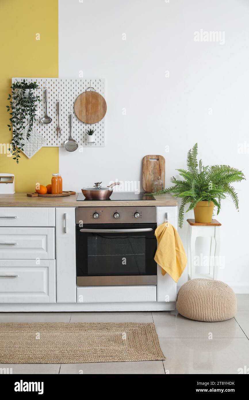 Interior of stylish kitchen with oven, white counters and pegboard ...