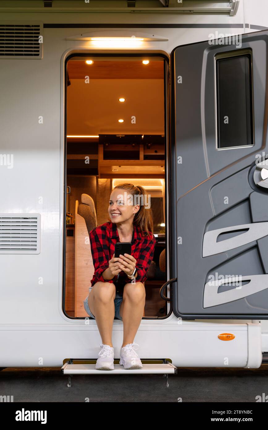 Woman sitting in the doorway of camper van while night parking. Rv camping. Stock Photo