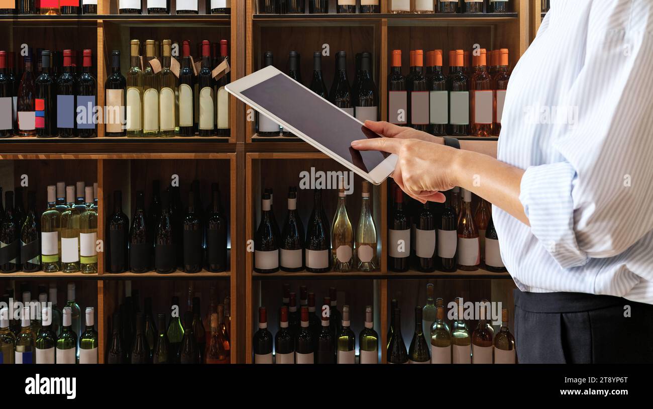 Wine shop manager using computer tablet while working at store. Stock Photo