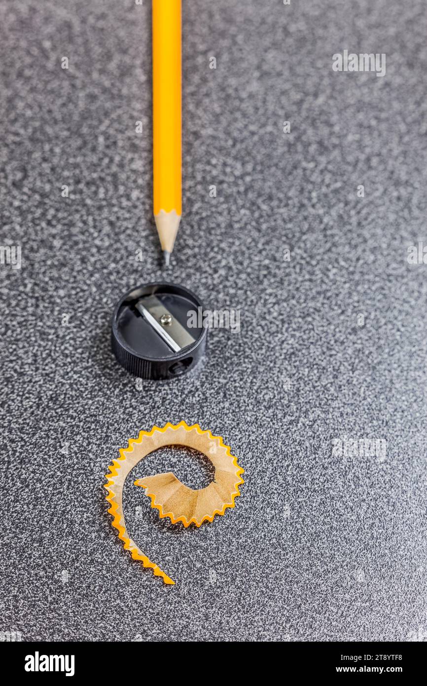 Close-up of a pencil, a pencil sharpener and a pencil shaving on desk Stock Photo