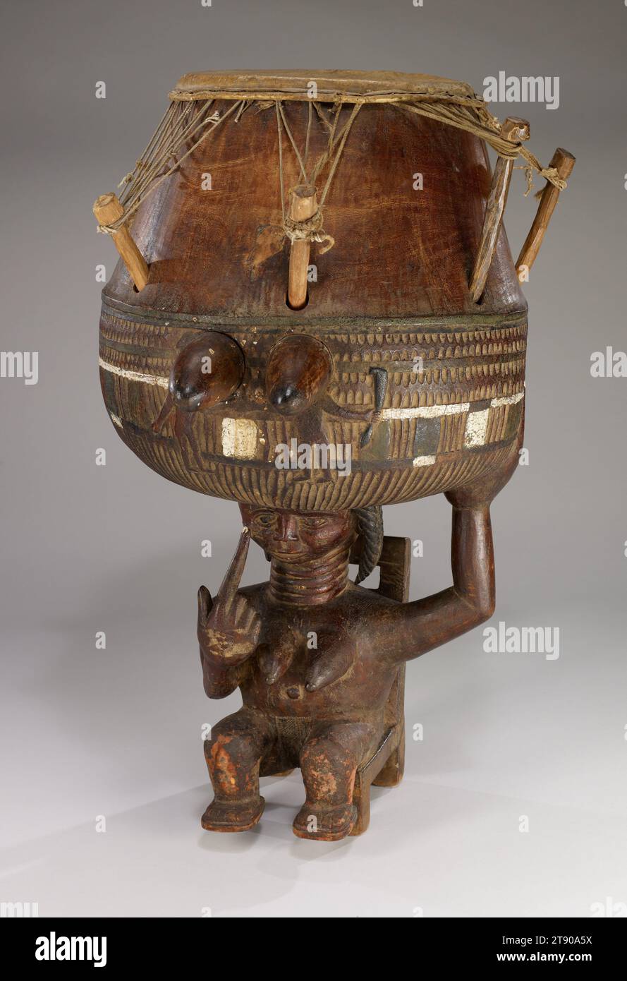 Drum, about 1950, 26 3/16 x 19 1/8 x 16 in. (66.52 x 48.58 x 40.64 cm), Wood, animal skin, string, pigments, Ghana, 20th century, Akan communities in southern Ghana have a tradition in which popular bands compete in instrumental, choral, and dance performances. The master drum, sometimes identified as the 'mother of the group,' is the musical and visual focal point of each band. The gesture of the woman, her finger pointing to her eye, may refer to the proverb, 'If you can hear, can you not also see''—emphasizing the importance of using all the senses. Or it may be a warning to the other bands Stock Photo