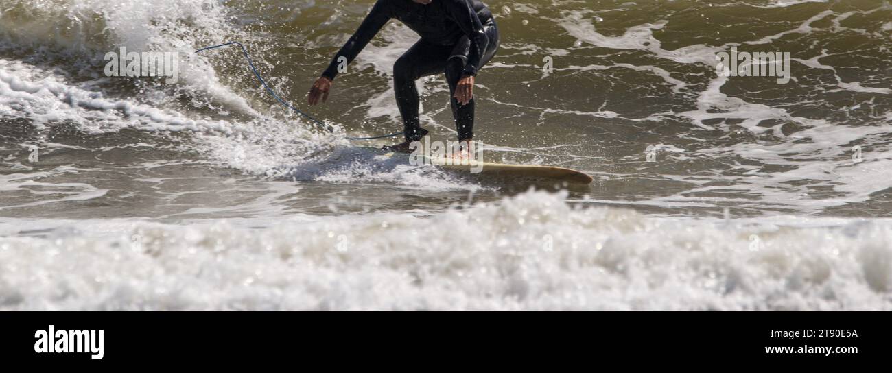 A man riding a wave on top of a surfboard. Stock Photo
