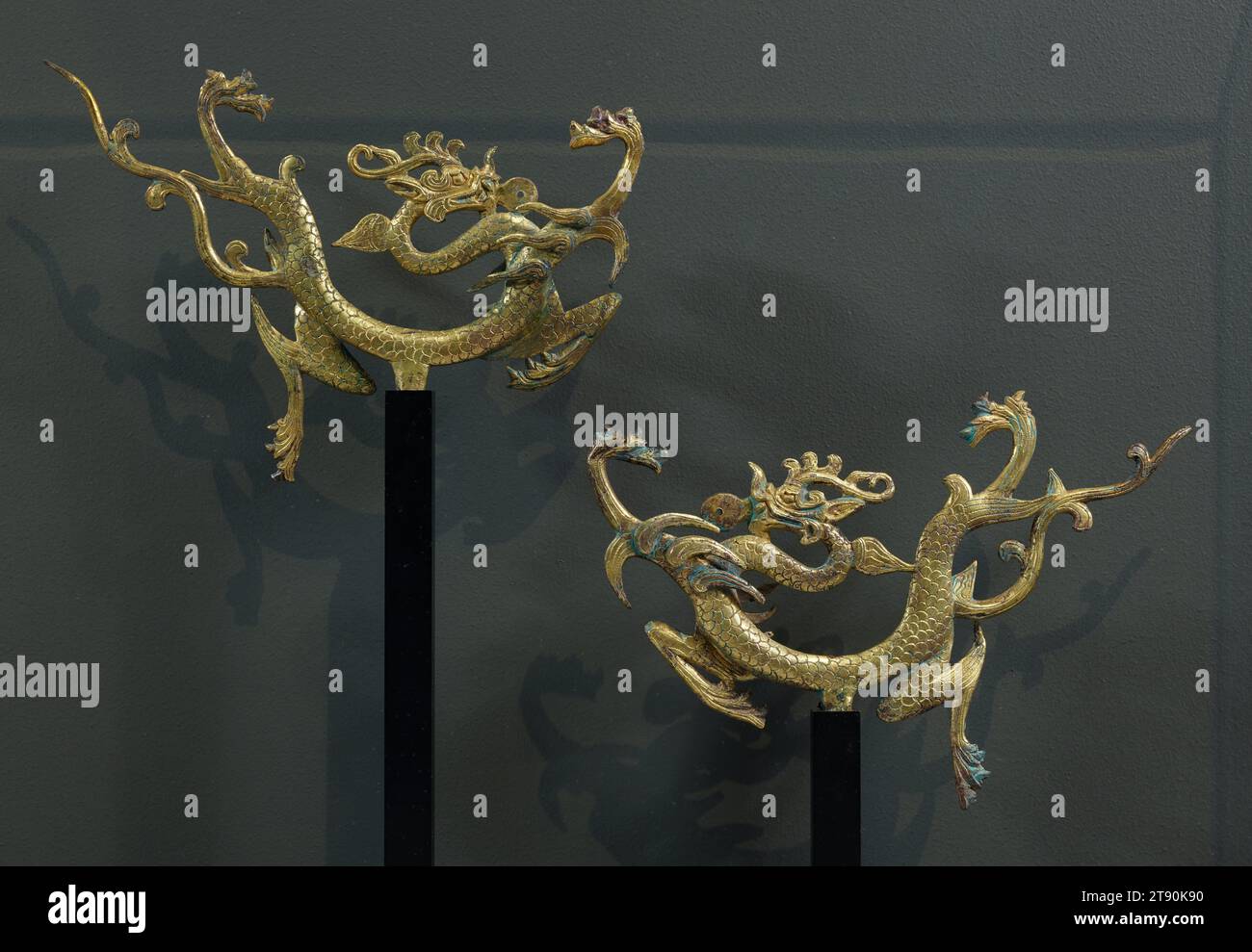 Flying Dragon, one of a pair, 8th century, 6 1/2 x 9 9/16 x 7/8 in. (16.5 x 24.3 x 2.2 cm), Gilt bronze, China, 8th century, The dragon is the universal emblem of China's cultural glory. As early as the Neolithic period, the Chinese considered this mythological creature to be an auspicious animal residing in heaven that provided rain and nourished life. By the late Bronze Age, the dragon was equated with the emperor, and in 221 BCE, Qin Shi Huang Di, the great unifier of China and builder of the Great Wall, proclaimed himself to be a descendent of the dragon. Stock Photo