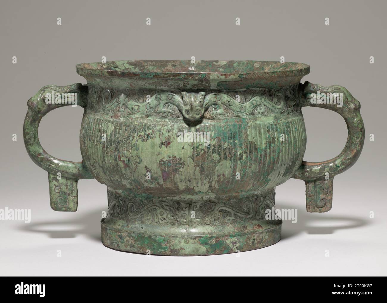 Gui (ritual food vessel), 11th-10th century BCE, 6 1/4 × 12 5/16 × 724 in. (15.88 × 31.27 × 1838.96 cm), Bronze, China, 11th-10 century BCE, This vessel form, known as gui, was used to hold food in ritual ceremonies during the Bronze Age. The band under the lip is a pair of bifurcated dragons, whose rounded, undulant double body is patterned with intaglio tulip-shaped designs. In the frieze encircling the foot two pairs of S-shaped dragons, on each side of the body, are arranged around relief ridges coaxial with the horned dragon head in the upper border. Stock Photo