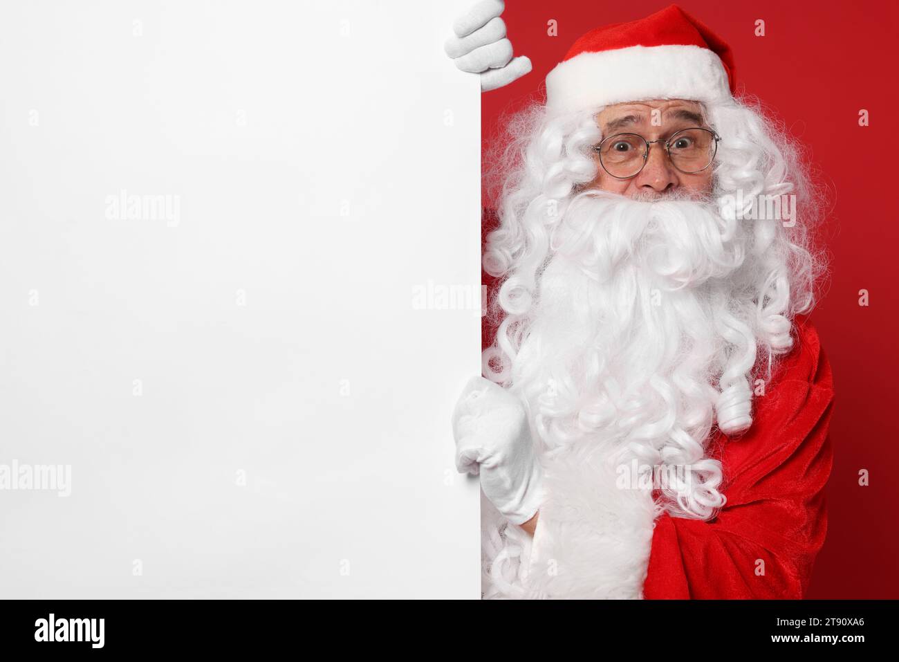 Santa Claus holding blank poster on red background, space for text ...