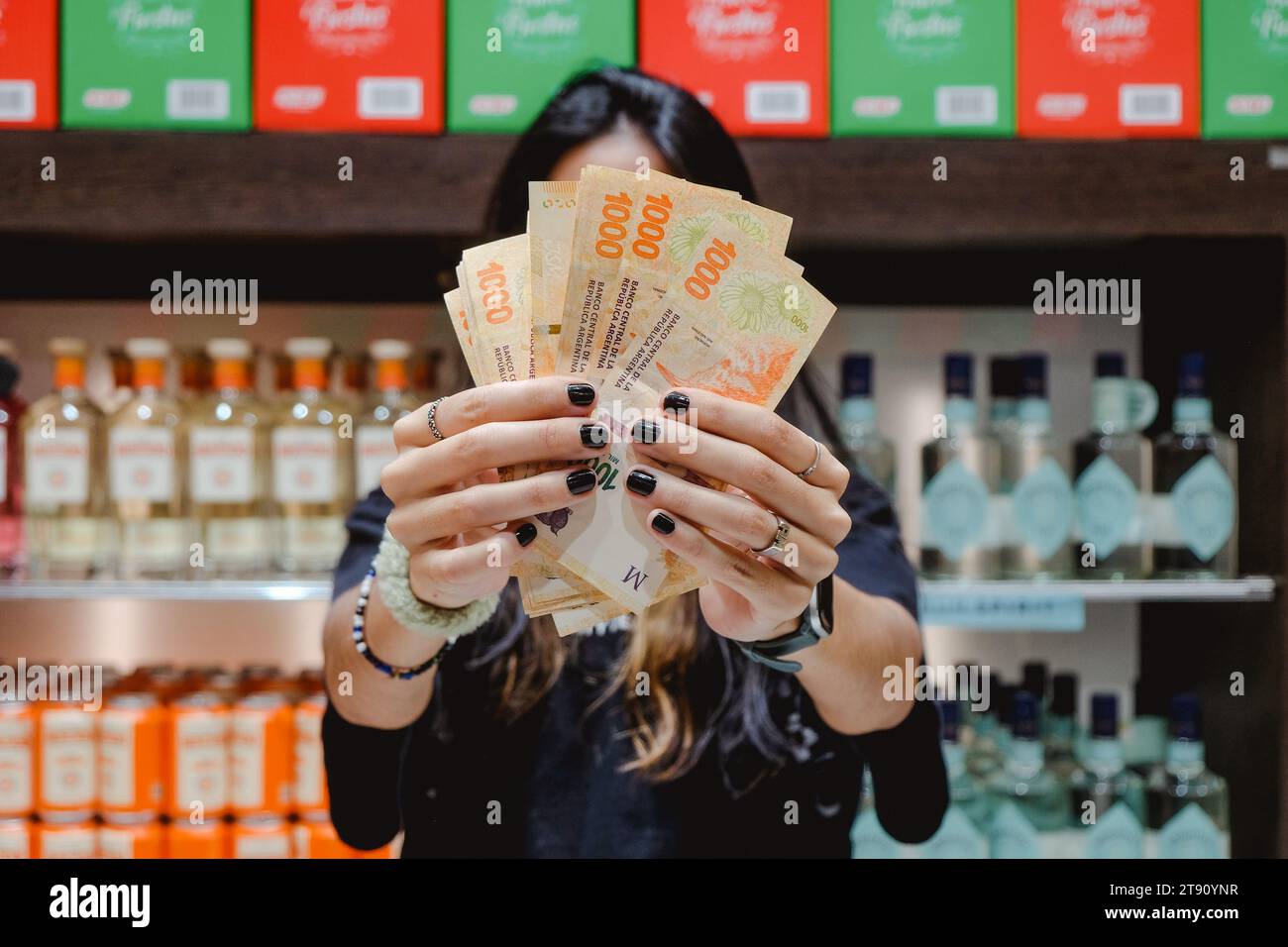 Anonymous Girl Holding Argentine Peso Bills In The Supermarket. Concept Of Inflation And Devaluation Of The Argentine Currency 2023 Stock Photo