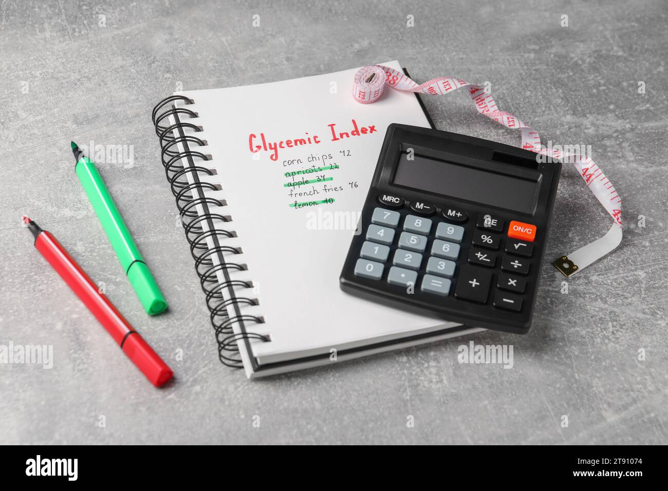 Glycemic Index. Notebook with information, markers, calculator and measuring tape on light grey table Stock Photo