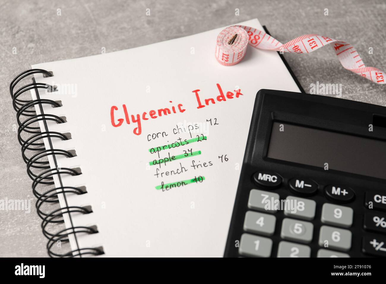 Glycemic Index. Notebook with information, measuring tape and calculator on light grey table, closeup Stock Photo