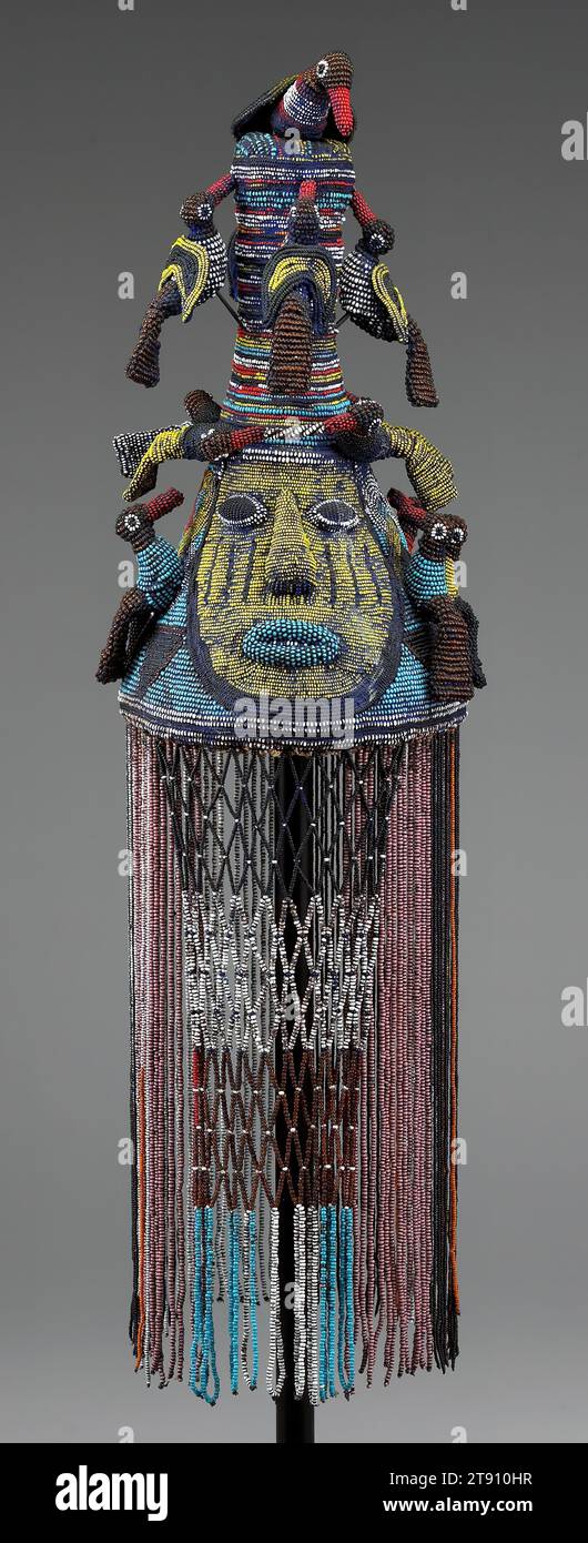 Crown, about 1920, L.15 (crown), L.15 (fringe) in., Glass beads, leather, canvas, wicker, Nigeria, 20th century, There’s a good reason why a Yoruba crown is always placed on the ruler’s head from behind or from the side: grave disaster could strike if the king sees inside the conical headdress, so potent is its power. For similar reasons, his subjects shouldn’t gaze upon his face, usually covered by a beaded veil to prevent such encounters. This crown is also adorned with royal birds, regarded as important messengers between the divine world and the earth Stock Photo