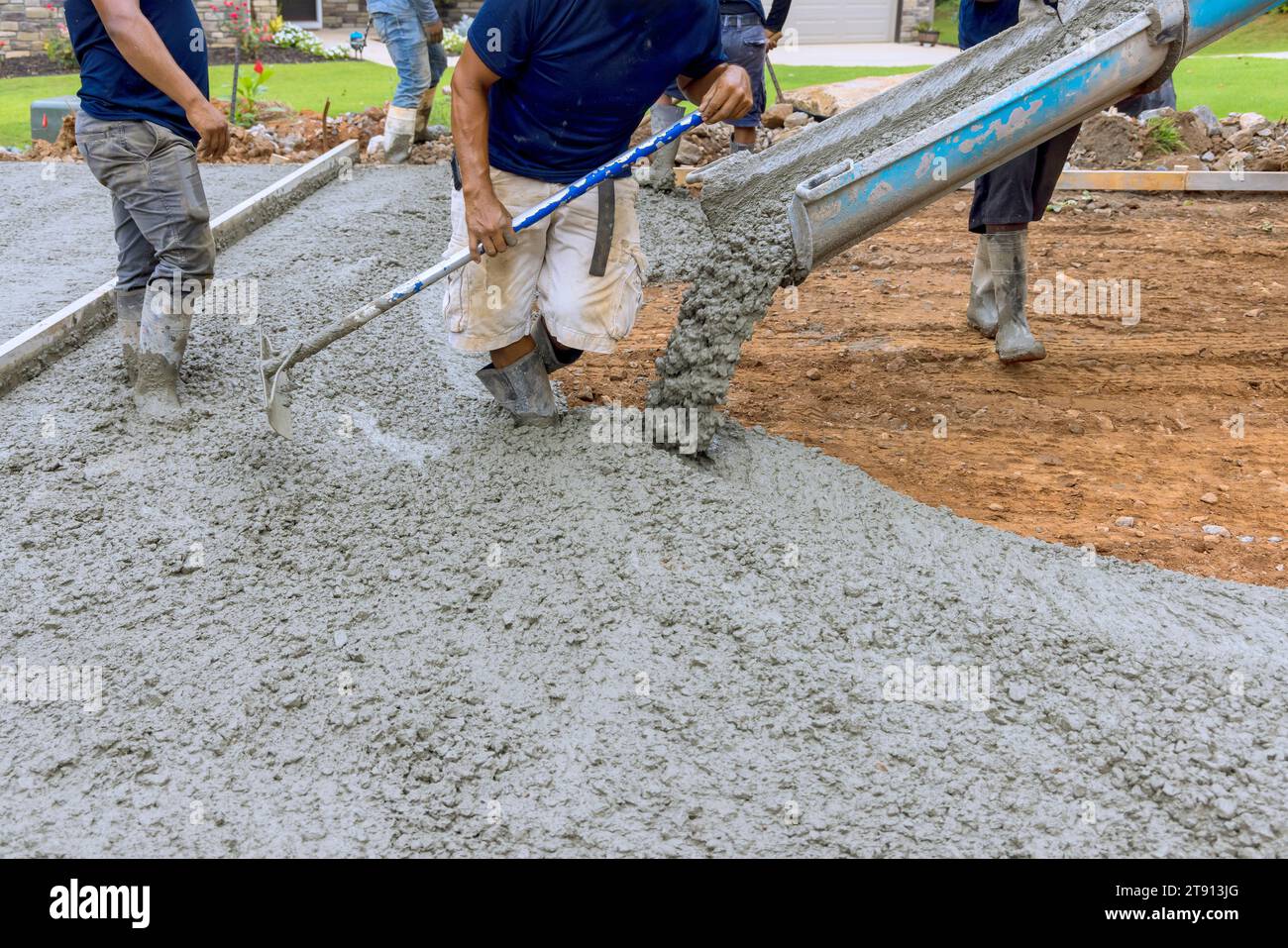 Using concrete mixing truck workers poured wet cement onto driveway of