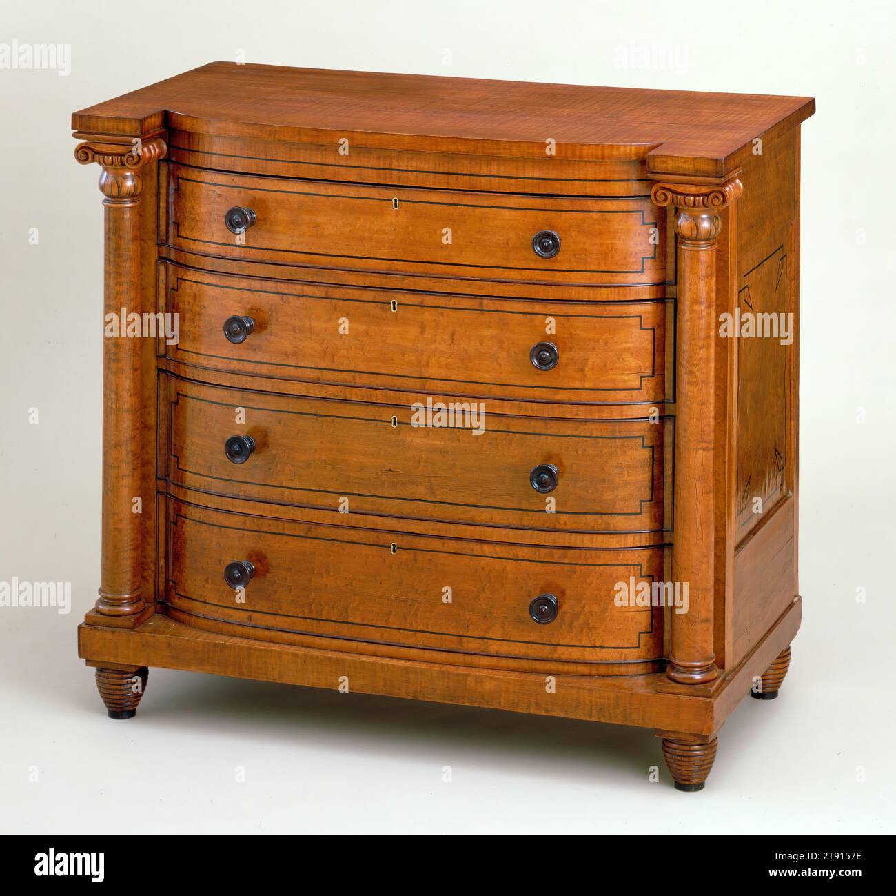Chest of drawers, c. 1825, 43 1/2 x 47 x 23 1/4 in. (110.49 x 119.38 x 59.06 cm), Bird's eye and tiger maple, pine, tulip, United States, 19th century, Chests of drawers with bowed fronts flanked by caryatid figures or columns, such as this one, are often attributed to the Philadelphia area, where a significant number are known to have been owned and made. The form reflects a strong influence from the French Empire, or Neoclassical style. This example differs from most in that it is made of maple with rosewood details, more commonly found on Biedermeier style furniture made at this time Stock Photo