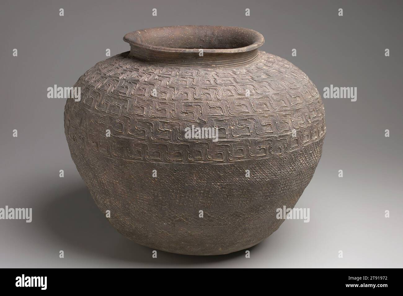 Storage Jar, 1122-772 BCE, 14 1/2 x 17 3/4 in. (36.8 x 45.09 cm), Stoneware with impressed decor, China, 12th-8th century BCE, This handbuilt vessel has been stamped with a wave pattern on its upper half and the lower half with a woven stamped pattern. The raised patterns create a greater amount of surface area on the exterior of the pot which in earthenware can cool the contents. This jar is made of stoneware which does not allow saturation of the clay body and thus no cooling occurs. A new technology at the time, high-fired stoneware is much more durable and thus the vessel will last longer Stock Photo