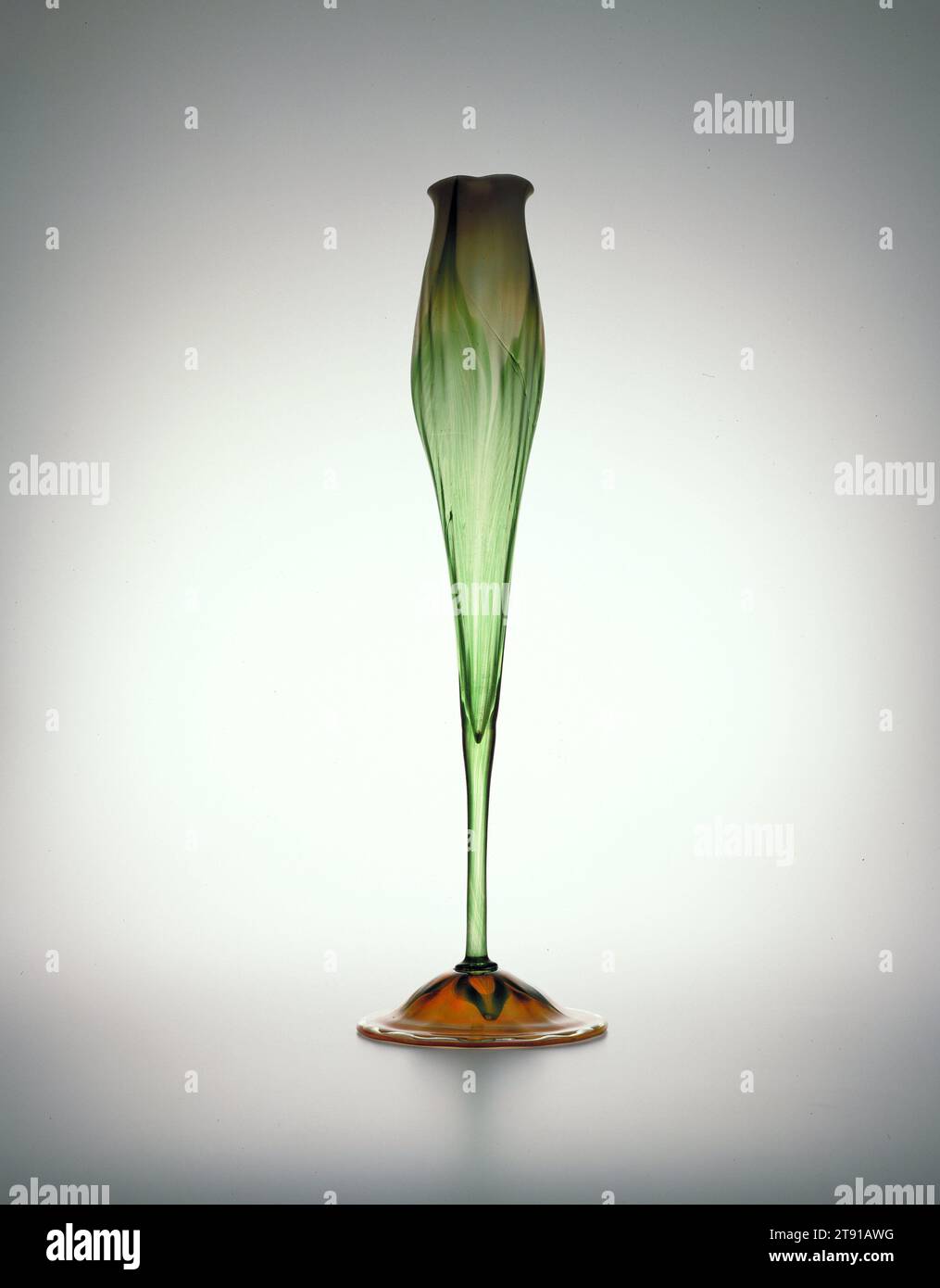 Floriform vase, c. 1890, Louis Comfort Tiffany; Manufacturer: Tiffany & Co., American, 1848–1933, 19 x 5 3/4 x 5 3/4 in. (48.26 x 14.61 x 14.61 cm), Blown iridescent glass, United States, 19th century, In 1894, the designer Louis Comfort Tiffany patented a process whereby hot glass was exposed to metallic fumes and oxides to create an iridescent surface. He named this glass Favrile from the Latin work faber, meaning artisan. Tiffany's Favrile glass was extremely popular internationally where it won honors at worlds fairs. Stock Photo