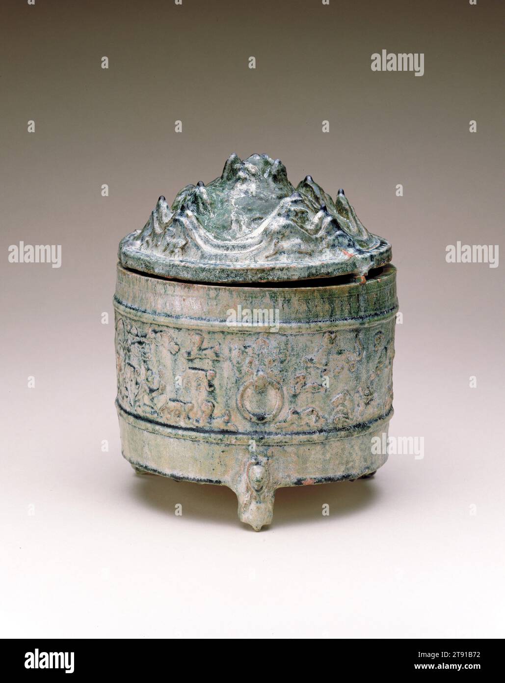 Lian (Cosmetic Container), 1st century, 10 1/8 x 7 7/8 x 7 7/8 in. (25.72 x 20 x 20 cm), Earthenware with molded decor under green glaze, China, 1st century, The cover of this jar depicts sacred mountains populated with animals of Han mythology, mainly dragons, tigers and bears. Around the main register is a landscape scene with hunters on horseback pursuing wild animals. Lian jars were used to store small items, especially cosmetics. The mountain peaks seen here and on the bo shan lu censer are inspired by popular Daoism and its fixation on immortality Stock Photo