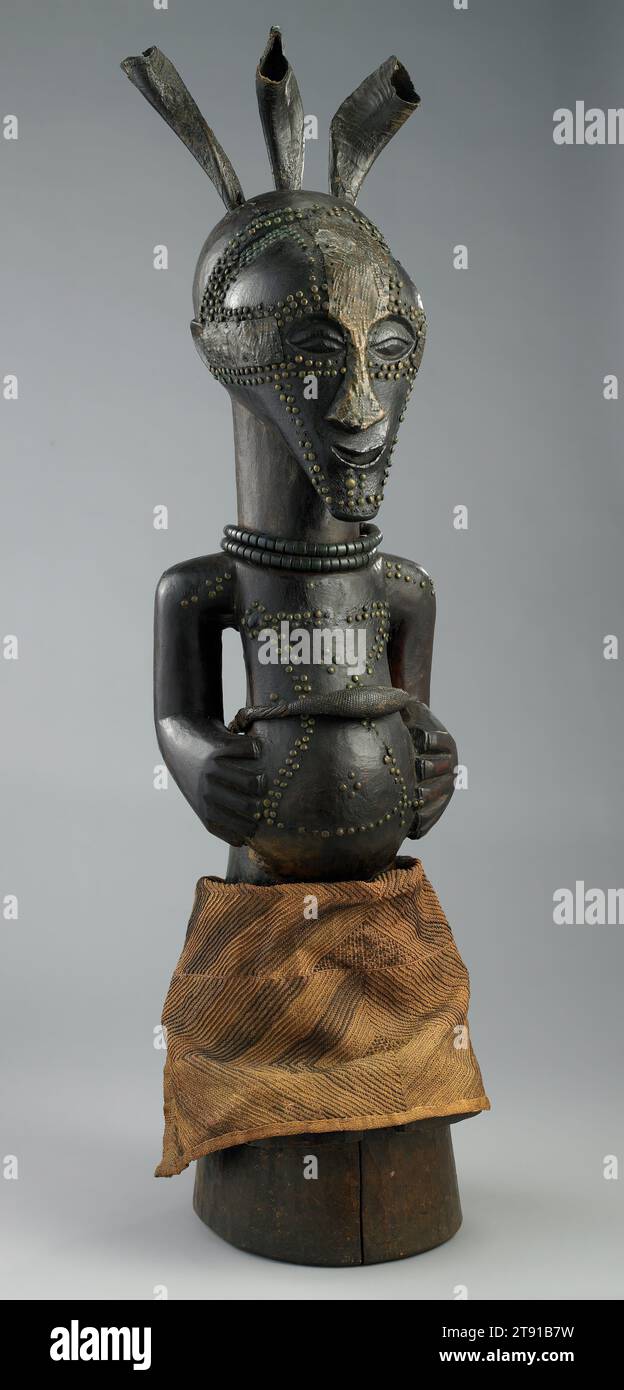 Power figure, c. 1900, 37 x 10 3/4 x 11 1/4 in. (94.0 x 27.3 x 28.6 cm), Wood, horn, brass tacks, metalwork, glass beads, fiber, Democratic Republic of the Congo, 19th century, In a small house at the edge of a Songye village, a ritual expert would have kept a large power figure. Contrary to the much smaller personal power figures, these communally owned ones were invoked for general welfare and protection against illness, sorcery, and war. The three horns atop this figure’s head once contained substances that enhanced its mystical power. Stock Photo