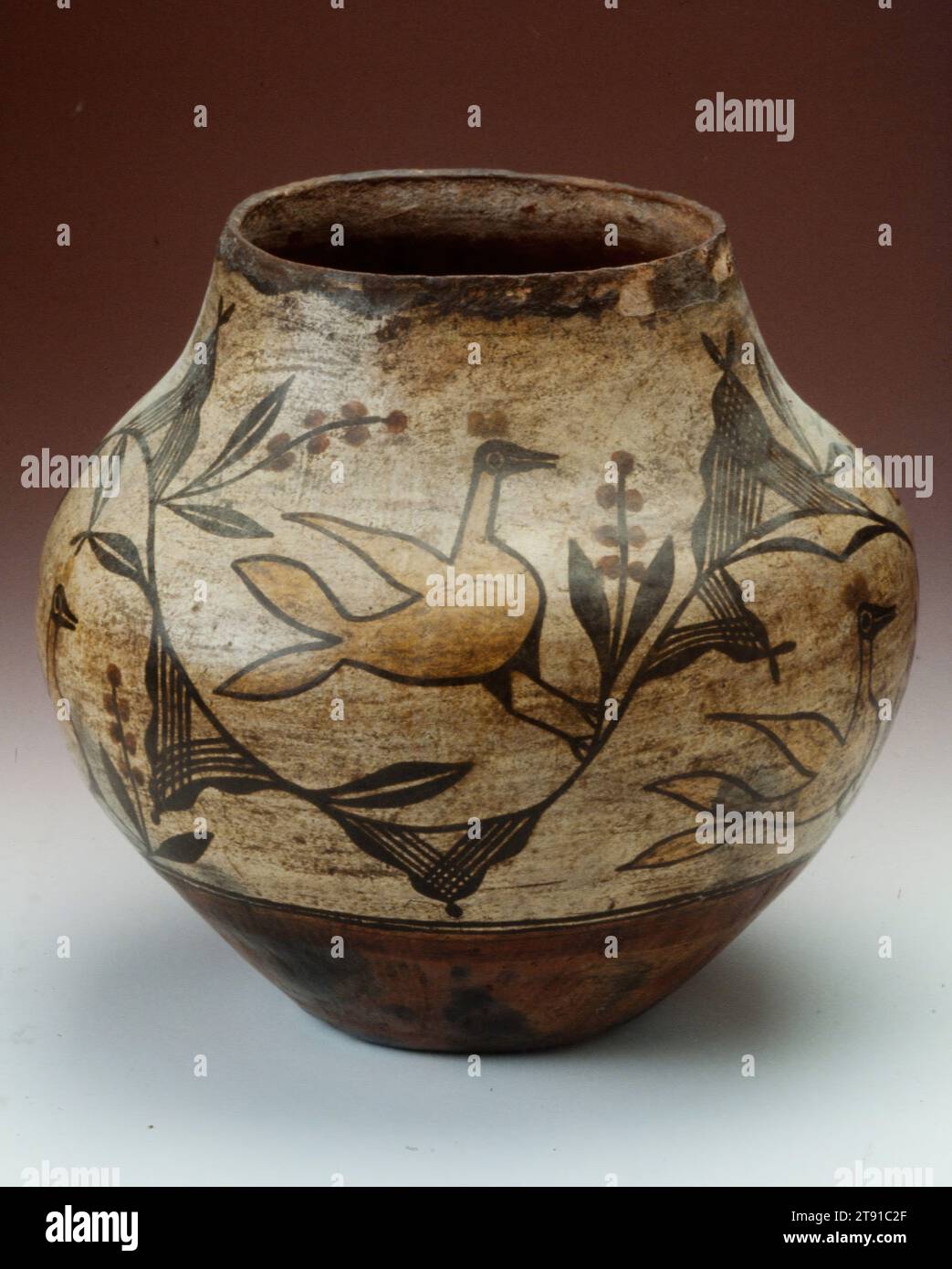 Vessel, 1910, 10 3/4 x 11 1/2 in. (27.31 x 29.21 cm), Ceramic, pigment, United States, 20th century, Zia artists often paint their beautiful ceramics with themes taken from the world around them, and have done so for centuries. Bird and feather imagery appears frequently on their hand-built vessels, usually accompanied by foliage, flowers and sometimes berries. The birds on this pot are modeled after roadrunners, an animal native to the Zia Pueblo area. Roadrunners are usually colored red by Zia artists, so these are especially striking for being yellow, which was an individual design choice Stock Photo