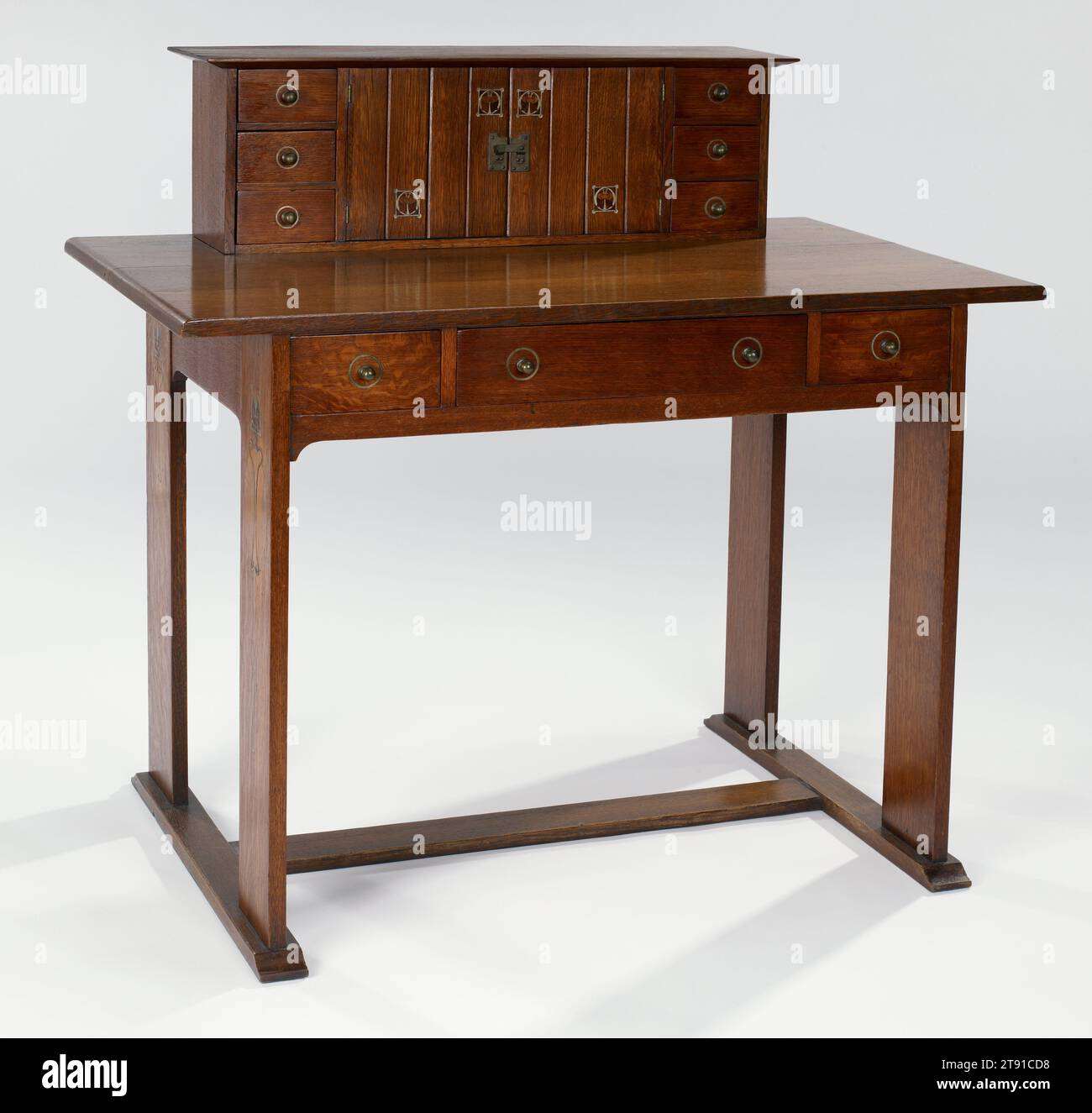 Desk, c. 1903, Craftsman Workshops of Gustav Stickley, American (Eastwood, New York), 1899-1916, 40-1/8 x 42 x 25-1/4 in. (101.9 x 106.7 x 64.1 cm), American white oak, pewter, copper, wood inlay, United States, 19th-20th century, Gustav Stickley hired Harvey Ellis in June 1903 to create illustrations of Arts and Crafts homes for his publication the Craftsman. Ellis produced imaginative drawings for possible interiors in the July and August 1903 and in January 1904, the month of his death. For these interiors Ellis depicted of furniture resembling Stickley's current production pieces Stock Photo