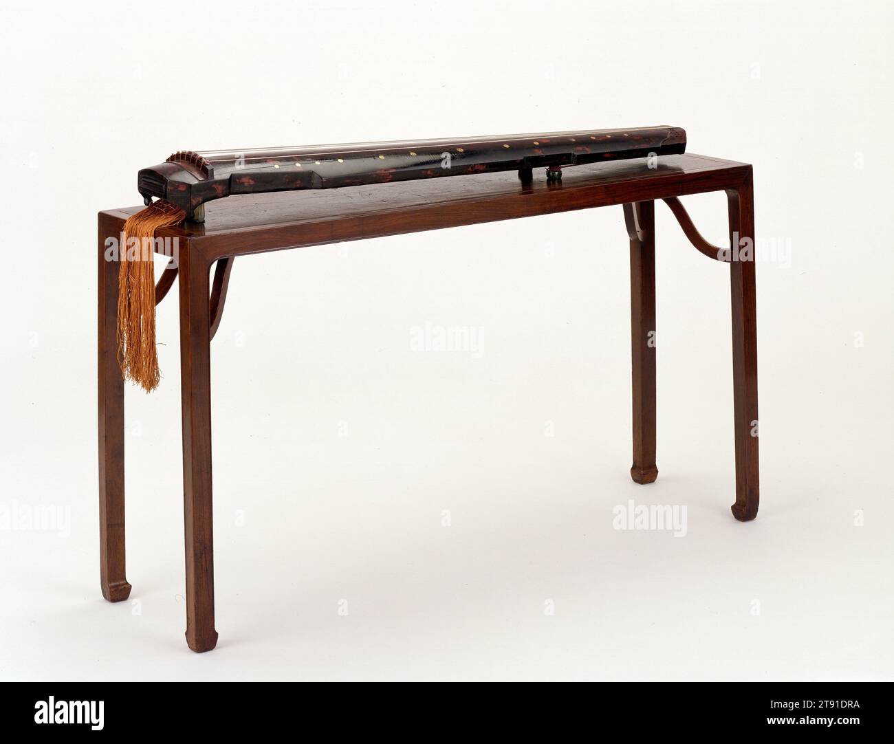 Zither (Qin), 1634 (dated by inscription), 47 x 7 x 3 1/2 in. (119.38 x 17.78 x 8.89 cm), Black and red lacquered wood with jade thumb screws, China, 17th century, The zither, or qin, has been regarded as a symbol of enlightenment by the Chinese since Confucian times (6th century BCE). By the seventeenth century, it was a required object in most scholars' studies, if only for display. This rare example has inscriptions on the bottom, including the title Zhong He ('middle harmony') and the number 57. Stock Photo