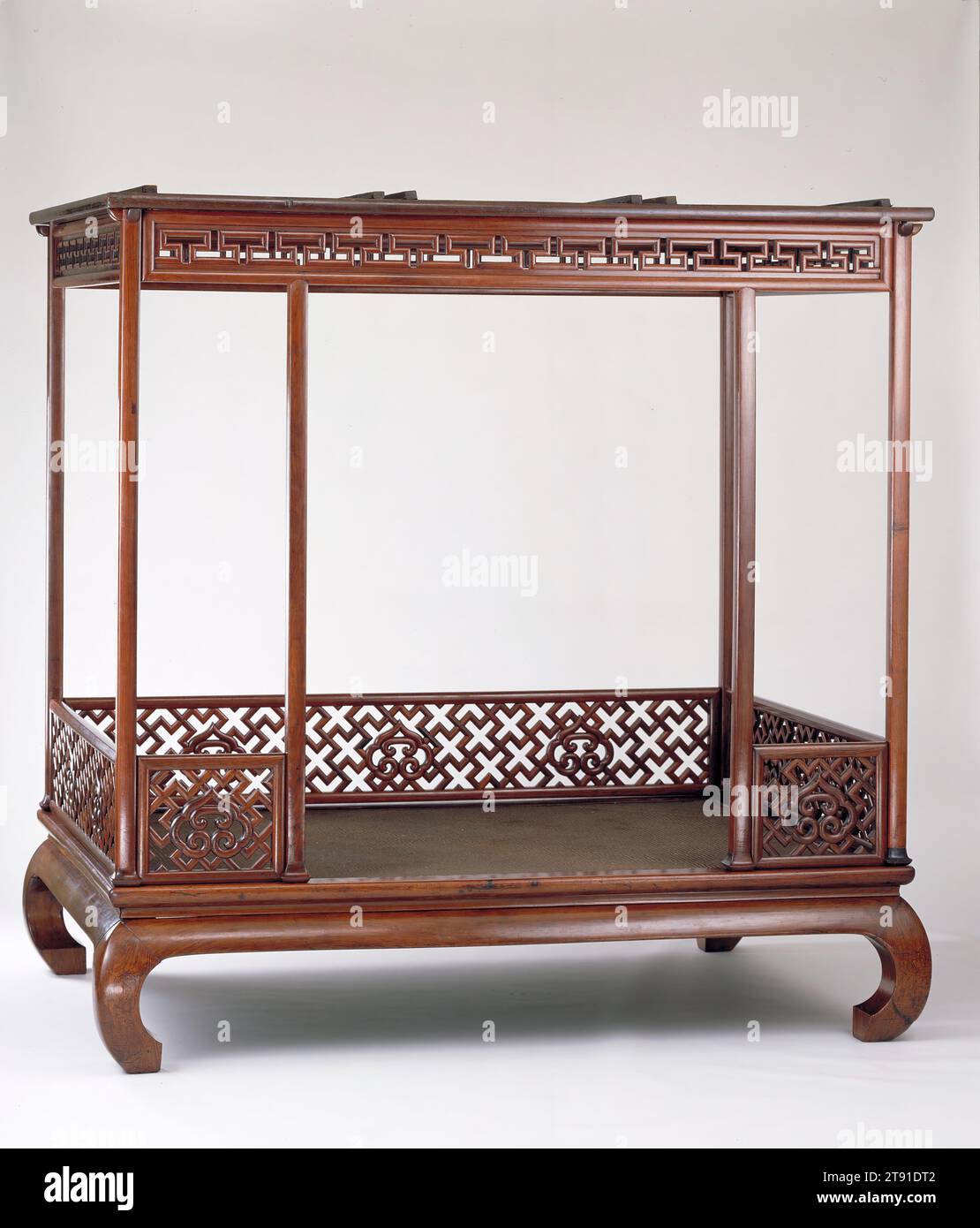 Six-Post Canopy Bed, early 17th century, 89 3/4 x 91 3/4 x 67 in. (227.97 x 233.05 x 170.18 cm), Huanghuali hardwood, China, 17th century, The canopy bed was one of the most important pieces of furniture in a Chinese household. It was generally ornamented with symbols associated with a long and happy marriage. Here, the railings are decorated with heart-shaped ruyi (the mythical wish-fulfilling symbol) set against a pattern of the Buddhist swastika signifying 'ten thousand,' which granted the owner the fulfillment of ten thousand wishes. Stock Photo