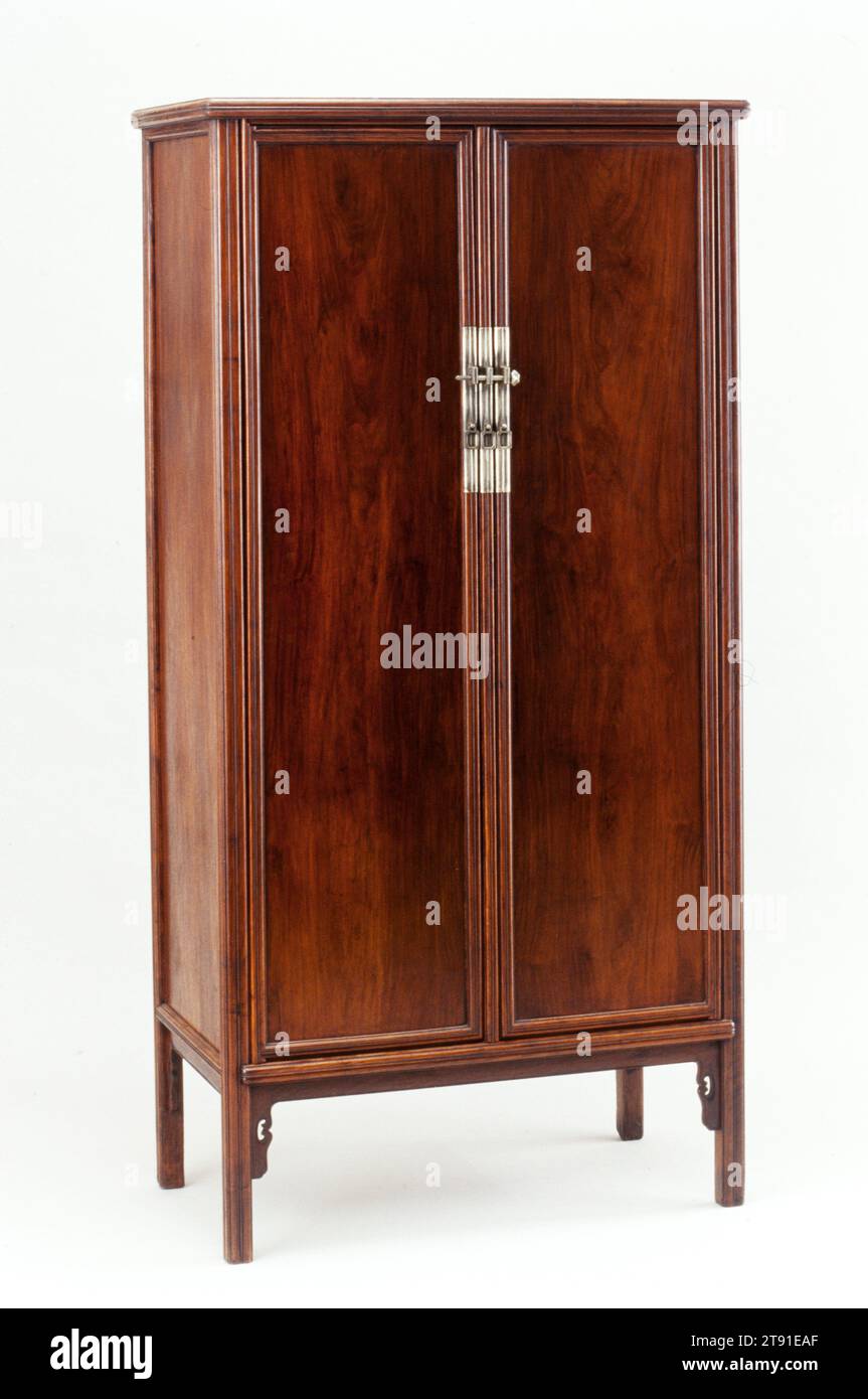 Large Tapered Cabinet, early 17th century, 73 7/8 x 36 1/8 x 19 3/4 in. (187.64 x 91.76 x 50.17 cm), Huang-hua-li hardwood and pai-tung hardware, China, 17th century, The classic, tall, tapered, round-corner cabinet encapsulates the essence of Ming-style furniture. Its exposed framework, simple floating panels, minimal hardware, inward taper, and pronounced verticality create an impression of serene calm and balance. The legs on this example, among the highest known, contribute a sense of lightness to a rather large volumetric form. As traditional Chinese homes did not have closets Stock Photo