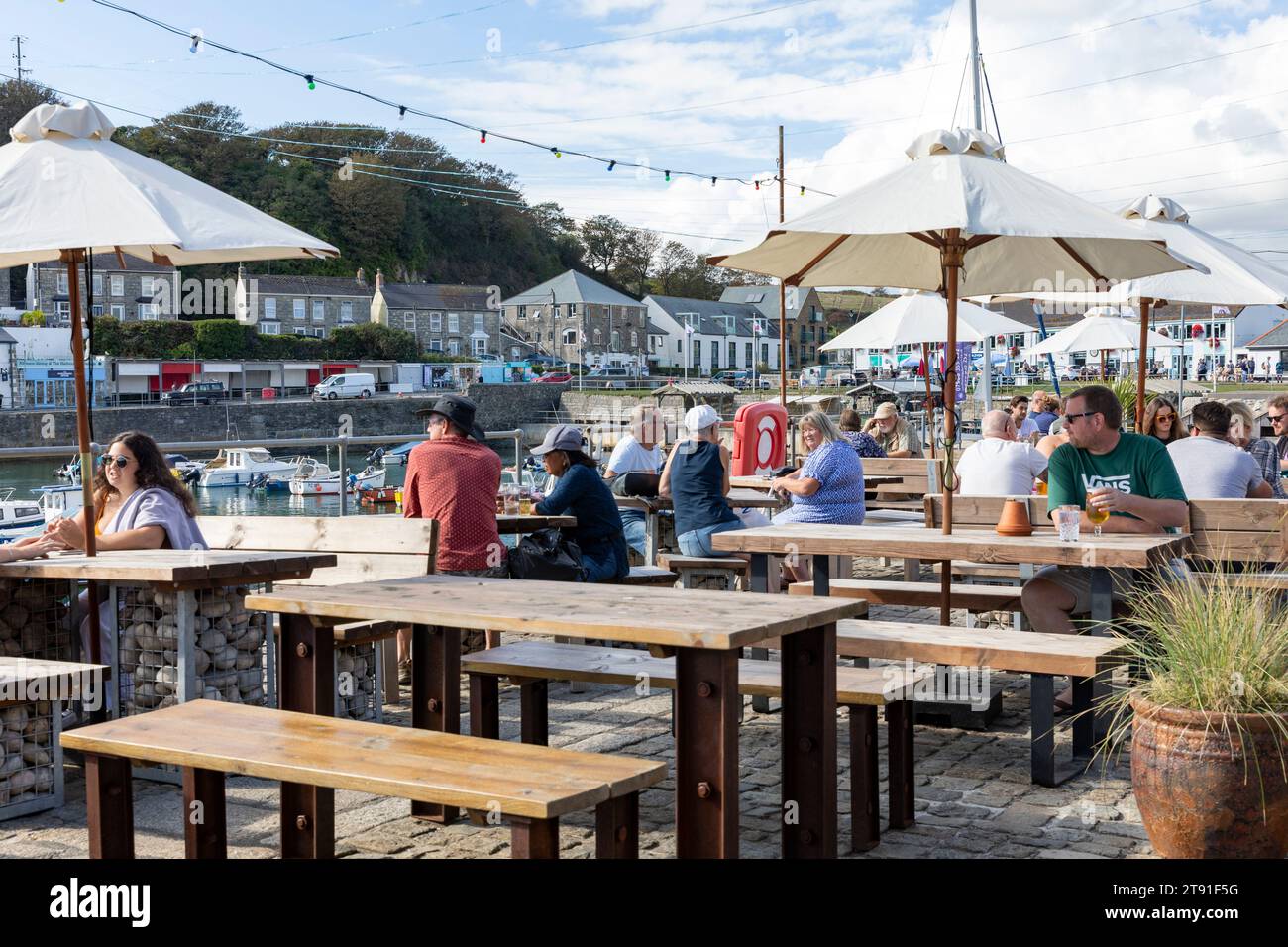 Porthleven pub, The Harbour Inn public house beer garden beside the harbour with people drinking outside,Cornwall,England,UK,2023 Stock Photo