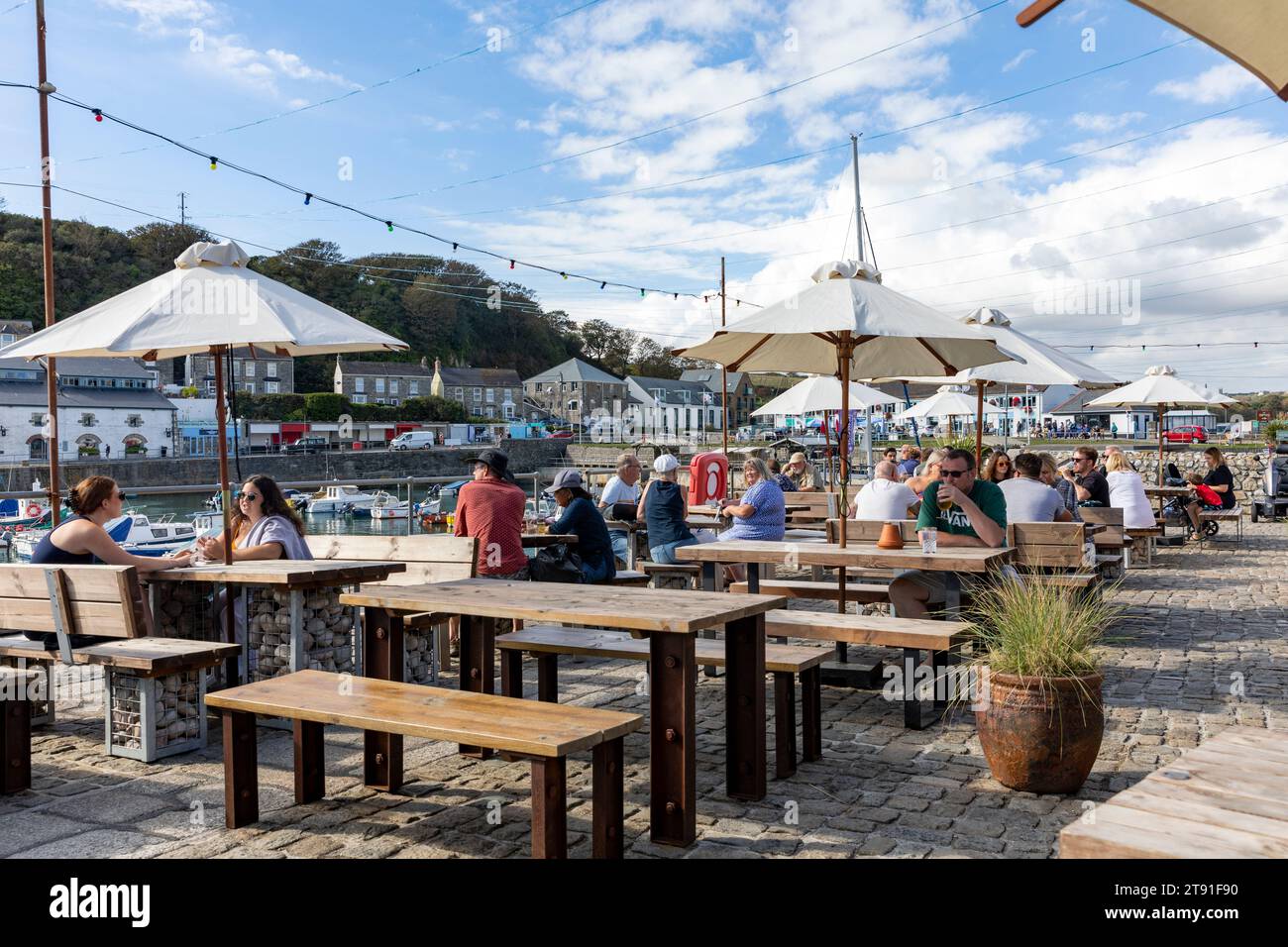 Porthleven pub, The Harbour Inn public house beer garden beside the harbour with people drinking outside,Cornwall,England,UK,2023 Stock Photo