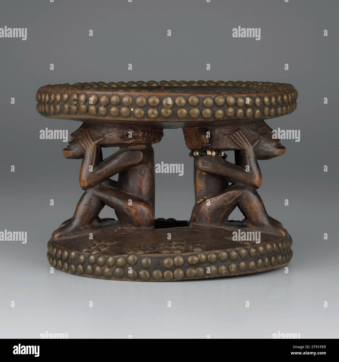 Stool, 19th-20th century, 5-11/16 x 8-1/8 x 7-13/16 in. (14.4 x 20.6 x 19.8 cm), Wood, brass tacks, beads, Democratic Republic of the Congo, 19th-20th century, Many African cultures, including the Chokwe, believe death is not an end, but merely a transition to the spirit world. Departed ancestors continue to play an active role in the life of the living, providing protection and guidance. The living try to ensure the good favor of their ancestors by respecting traditions and providing offerings of food and drink. The figure in these Chokwe stools is an ancestor holding her head in sorrow. Stock Photo