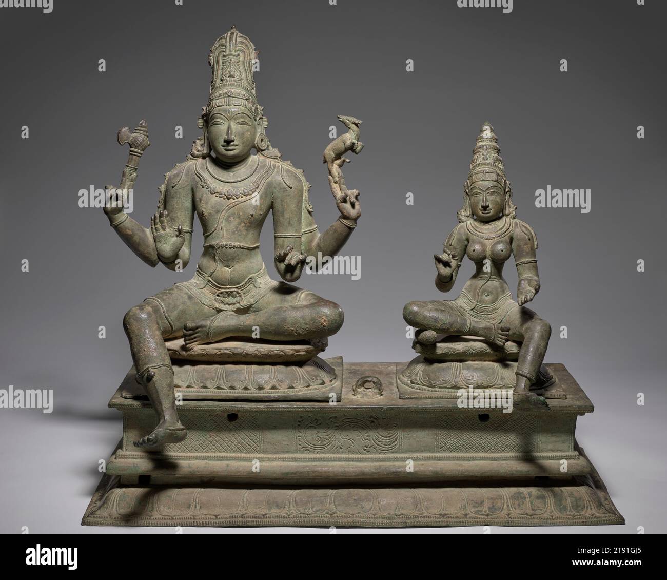 Somaskanda (Holy Family), 13th-14th century, 23 1/4 x 26 1/4 x 13 in. (59.06 x 66.68 x 33.02 cm), Bronze, India, 13th-14th century, Shiva and his wife Uma sit next to each other on double lotus pedestals, between them a residual remnant of their small child, Skanda, now missing from the magnificent bronze. The standard format—known as Somaskanda—arose as early as the 6th century in temples from Tamil Nadu, and remains Shiva’s main manifest form today. In south Indian temples, bronze images play a huge role in devotional practice, where they are treated as living embodiments of the gods. Stock Photo