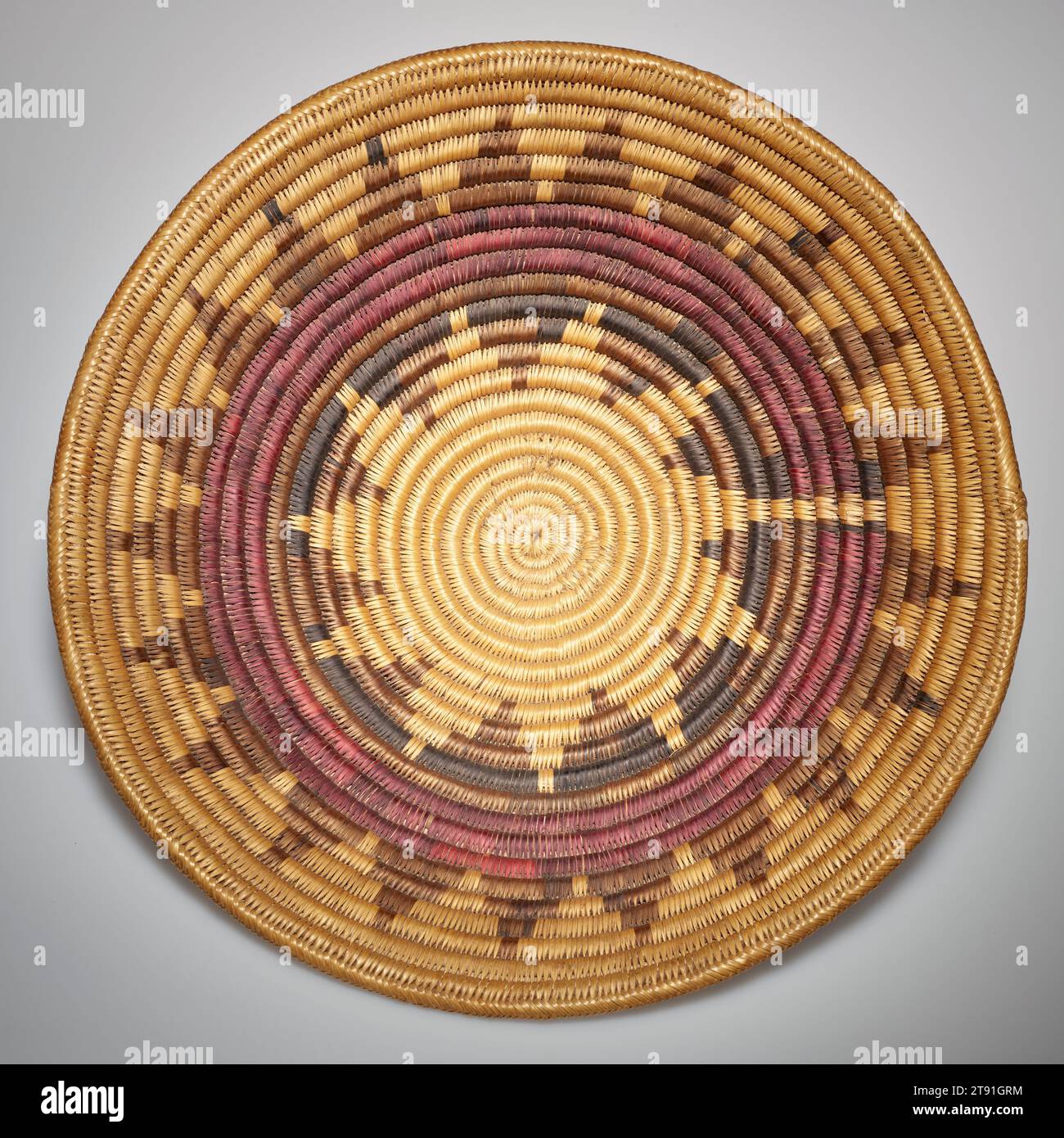 Basket, early 20th century, 16 1/4 x 16 1/4 in. (41.28 x 41.28 cm), Plant fibers, United States, 20th century, Although making baskets is not a vital role of Diné culture, baskets serve many important functions in their ceremonies. The Utes and Southern Paiutes, for example, have made wedding baskets in great quantity for trade with the Diné since before 1890. They are shallow in form with radiating designs and are made from sumac. The colors and designs of these baskets have symbolic meaning. The center represents Diné ancestry and the beginning of life. Stock Photo