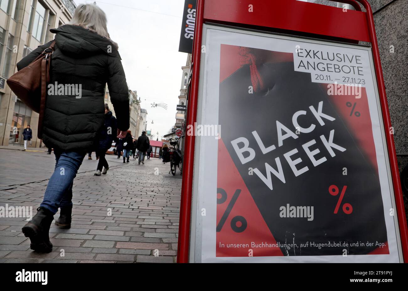 Rostock, Germany. 21st Nov, 2023. A woman walks past a store on the boulevard, a sign reading "Black Week" advertises special offers. The Northern German Retail Association plans to hold a virtual Christmas press conference on 22.11.2023 to provide information about the upcoming Christmas business in the retail sector. Christmas sales are the strongest period in terms of turnover in many retail sectors. Credit: Bernd Wüstneck/dpa/Alamy Live News Stock Photo