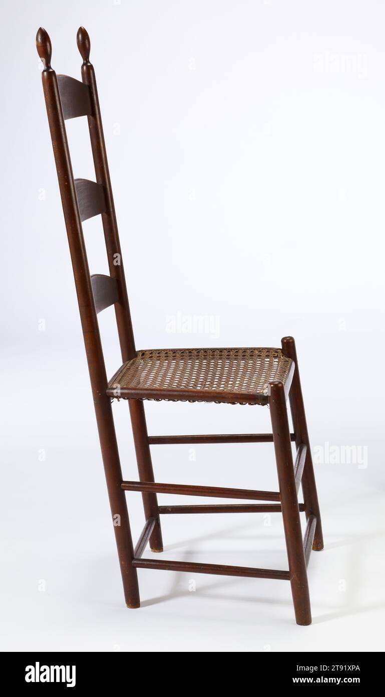 Shaker side chair, c. 1840, 41 1/4 x 18 x 13 1/2 in. (104.78 x 45.72 x 34.29 cm), Wood, cane, United States, 19th century, This chair was used by brothers and sisters in the Shaker community of Enfield, CT (1793-c.1918). Similar to chairs from other Shaker communities, like Canterbury, New Hampshire and Harvard, Massachusetts, this object is almost entirely comprised of lathe-turned posts and stretchers and has noticeably graduated rear slats. The slight slant to the legs allows one to lean back in the chair, supported by rear tilts or ball-and-socket feet at the bottoms of the rear stiles Stock Photo