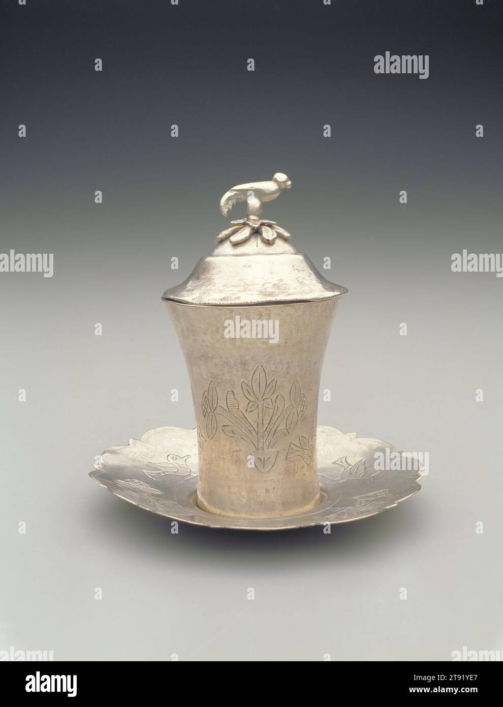 Kiddush (sanctification) cup with lid and saucer, c. 1920, 5 11/16 x 5 1/2 in. (14.45 x 13.97 cm), Silver, Iraq, 20th century, This covered cup from Iraq would have been used for drinking wine during kiddush, literally sanctification, a prayer said over wine during the Sabbath or other holiday. The floral decorations and stylized bird motif on the cover are common Middle Eastern design motifs Stock Photo