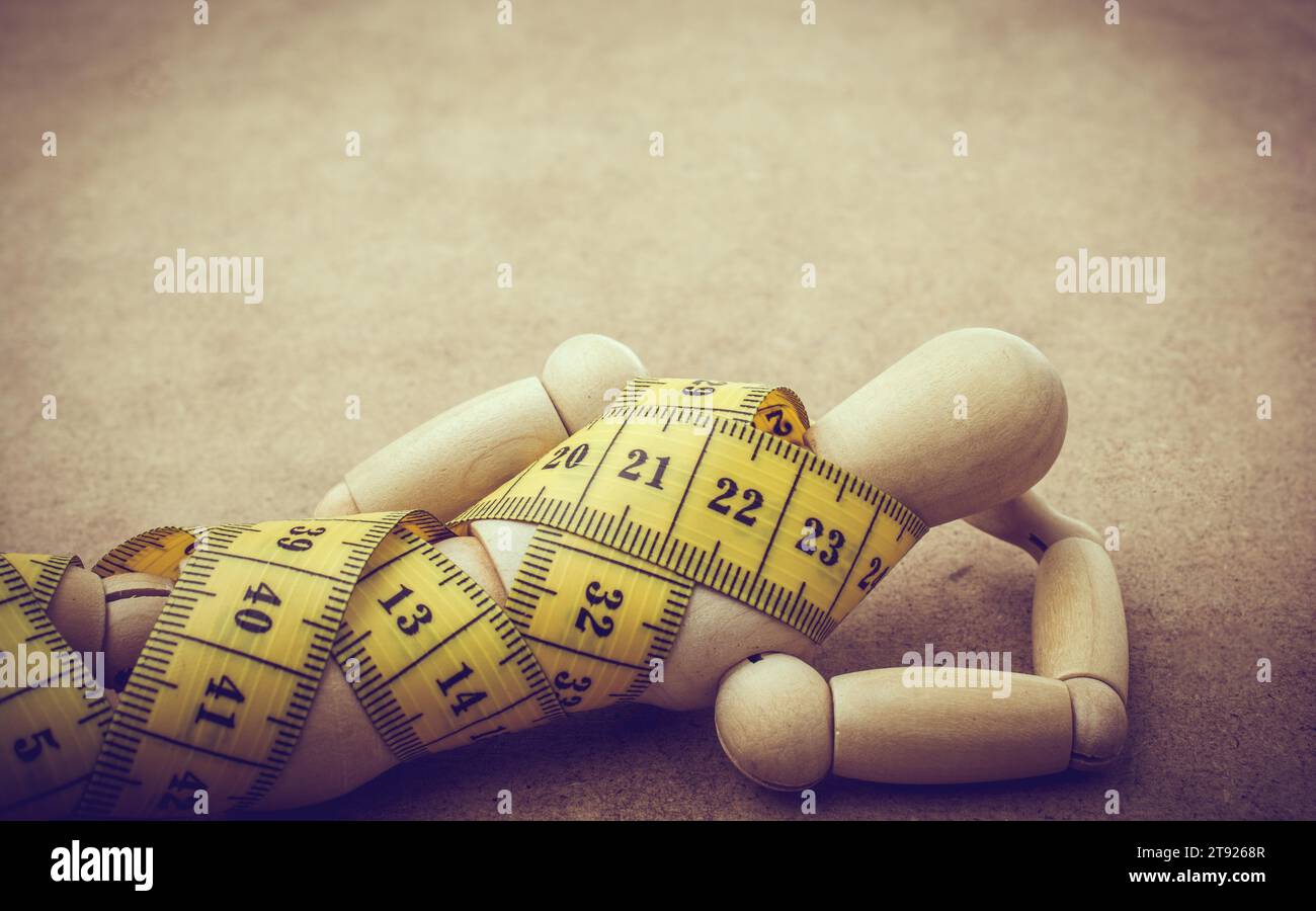Yellow color measuring tape wrapped on wooden man Stock Photo