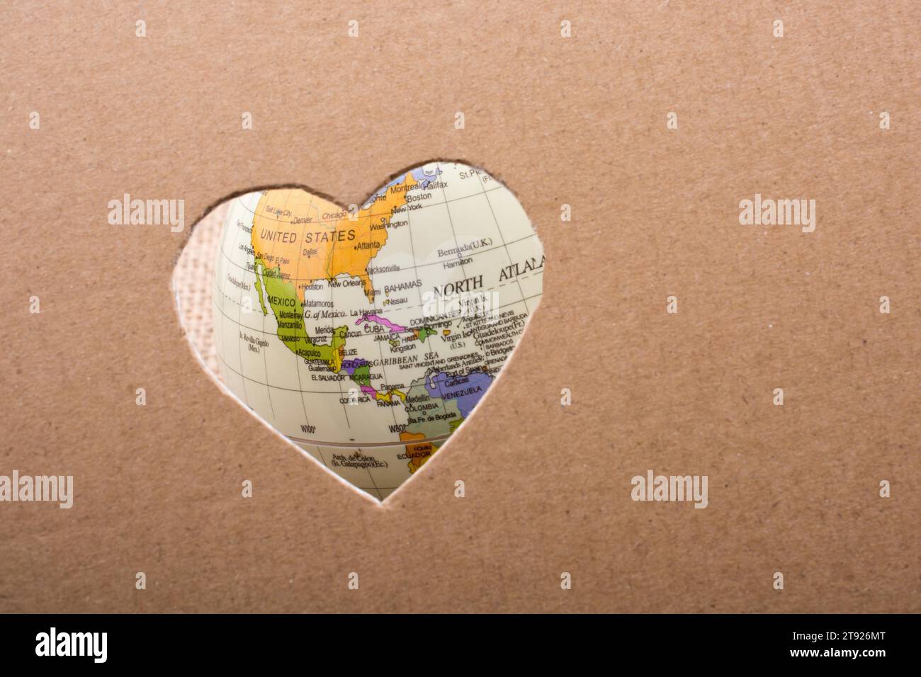 Globe seen through the heart shape hole on paper Stock Photo