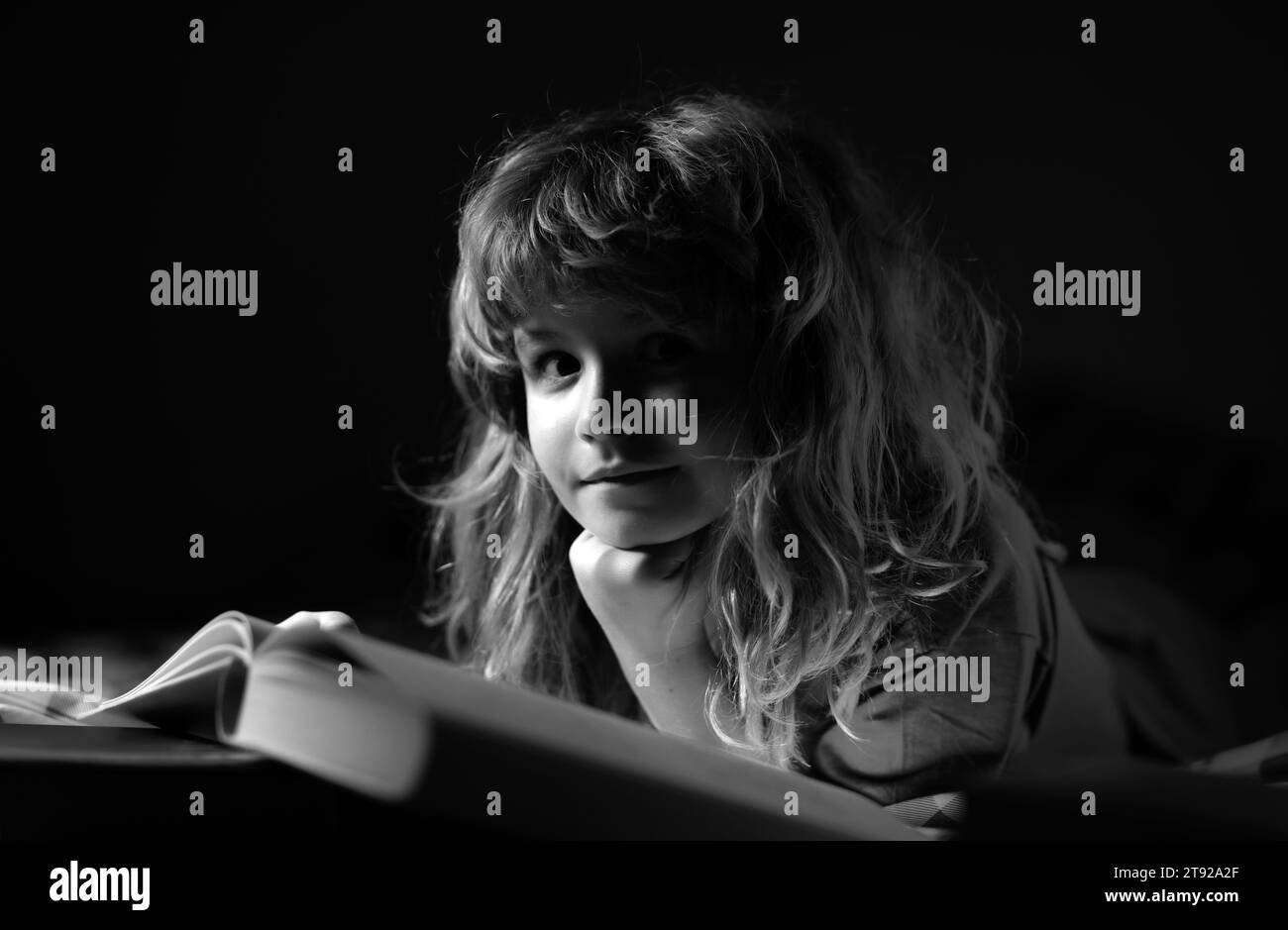 Kid reading bedtime story in dark room. A little cute boy reading a