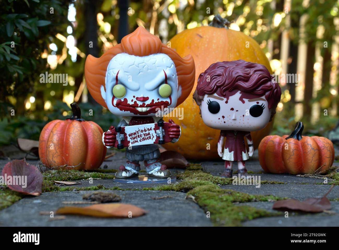 Funko Pop action figures of Pennywise clown and Beverly Marsh from horror movie It. Halloween, spooky season, pumpkins, decor, moss, autumn leaves. Stock Photo
