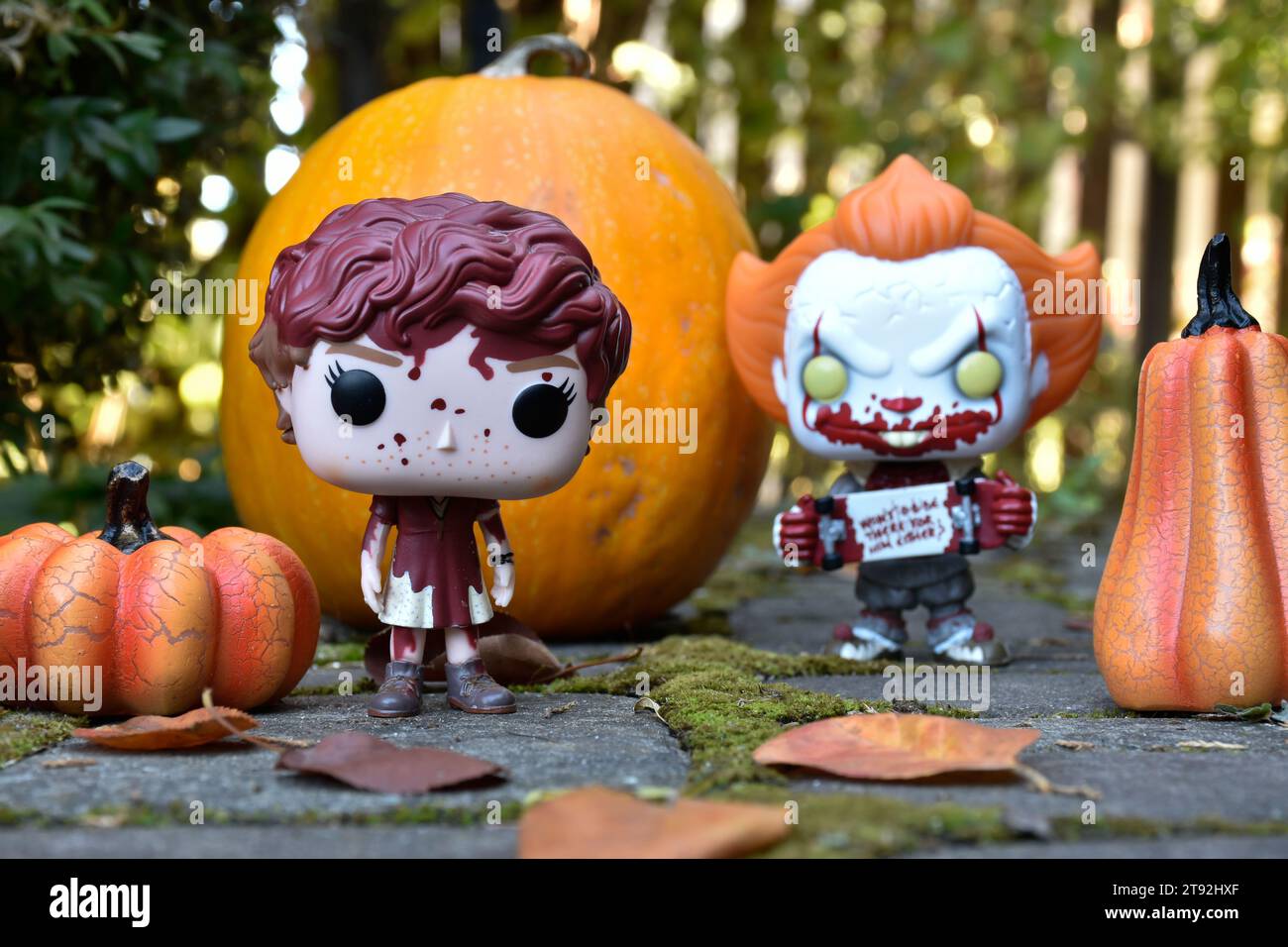 Funko Pop action figures of Beverly Marsh and Pennywise clown from horror movie It. Halloween, spooky season, pumpkins, decor, moss, autumn leaves. Stock Photo
