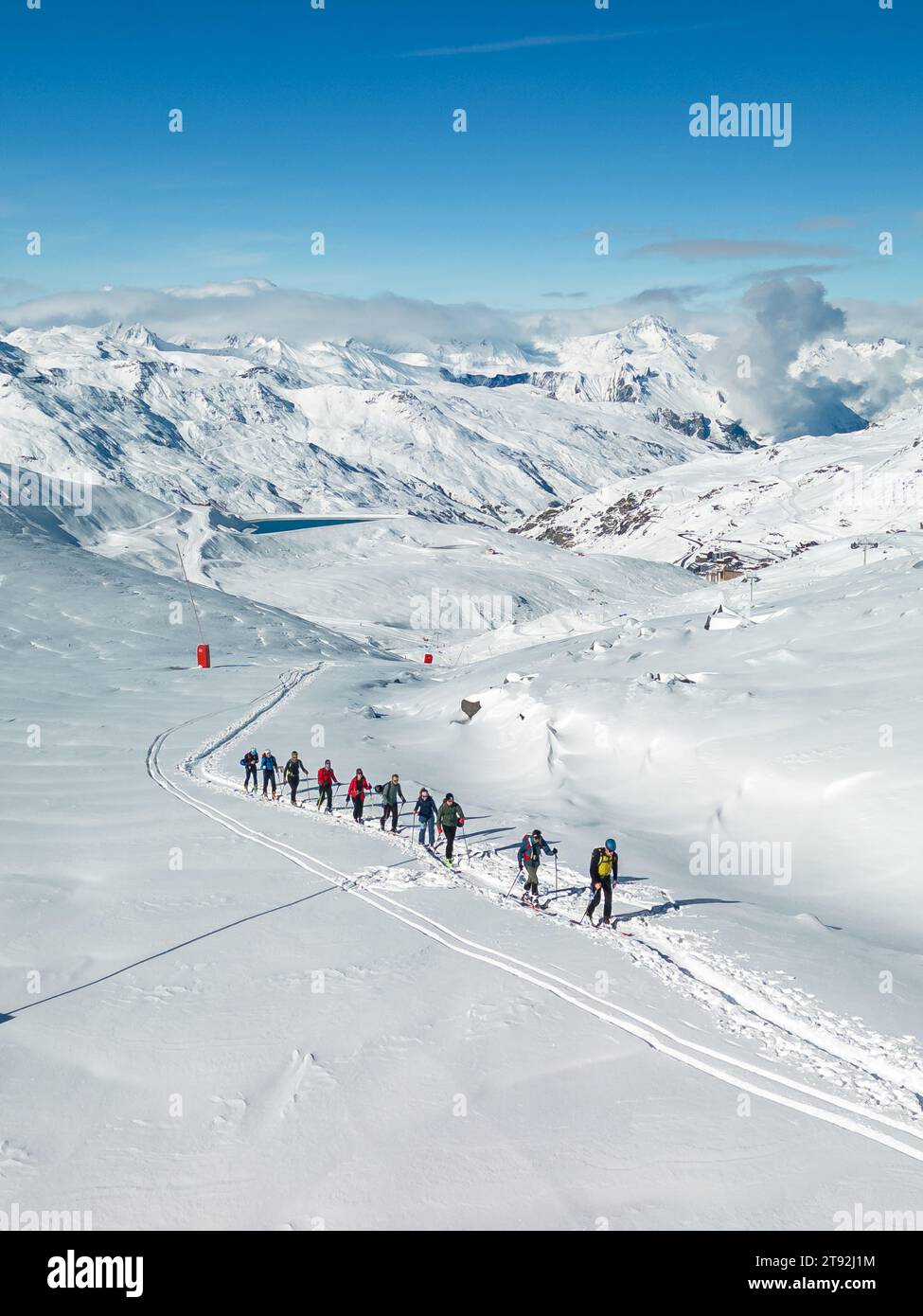 A drone captures tourists skiing in Val Thorens amid snowy landscapes, framed by a brilliant blue sky. Stock Photo