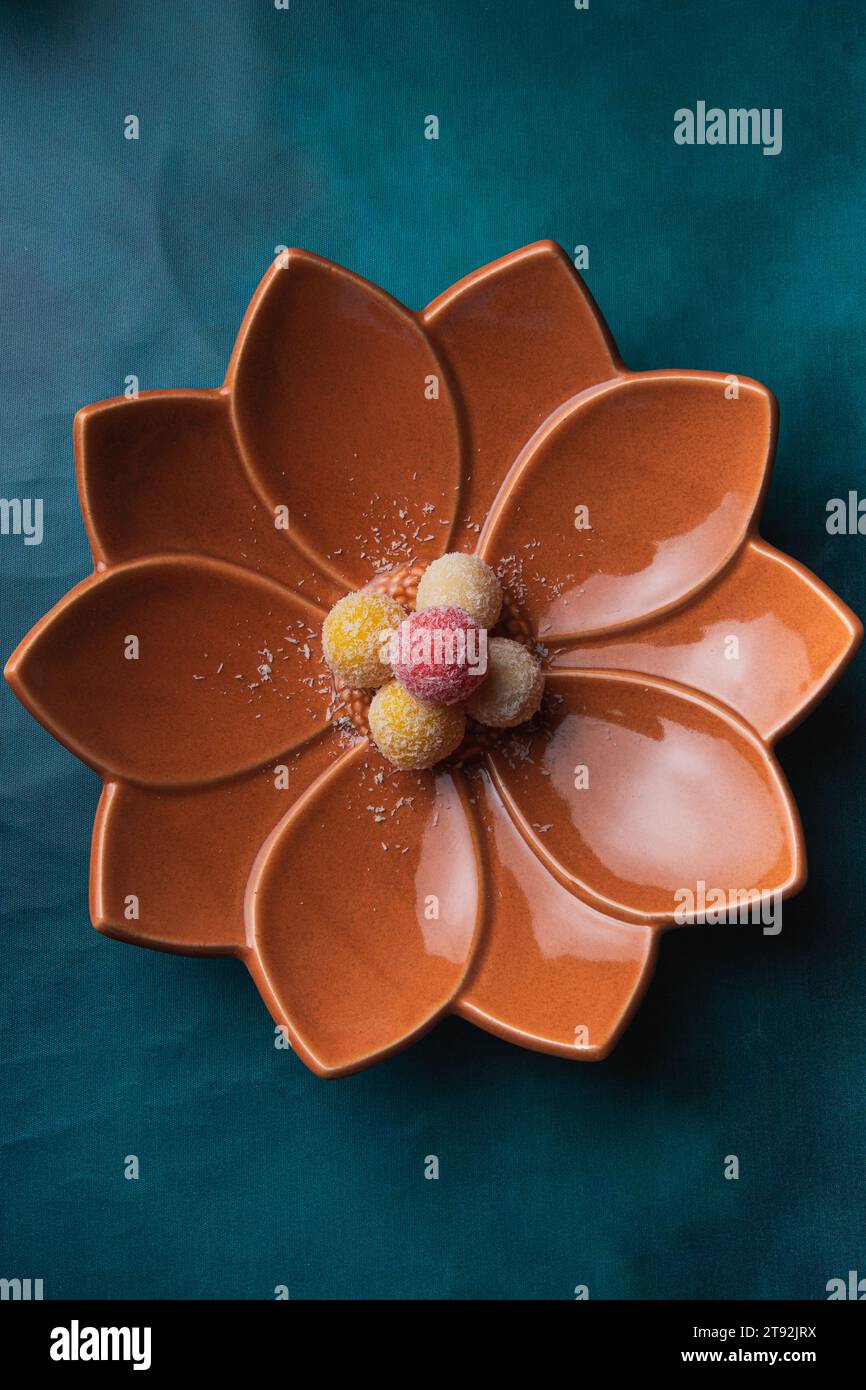 A close-up of a porcelain flower-shaped bowl resting atop a pale turquoise tablecloth Stock Photo