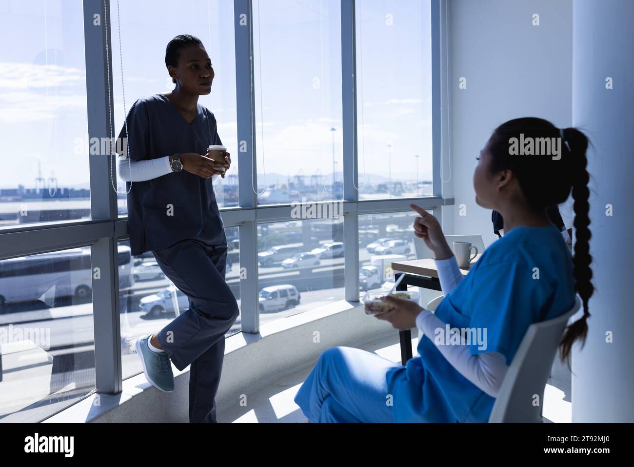 Diverse male and female doctors talking, drinking coffee and eating