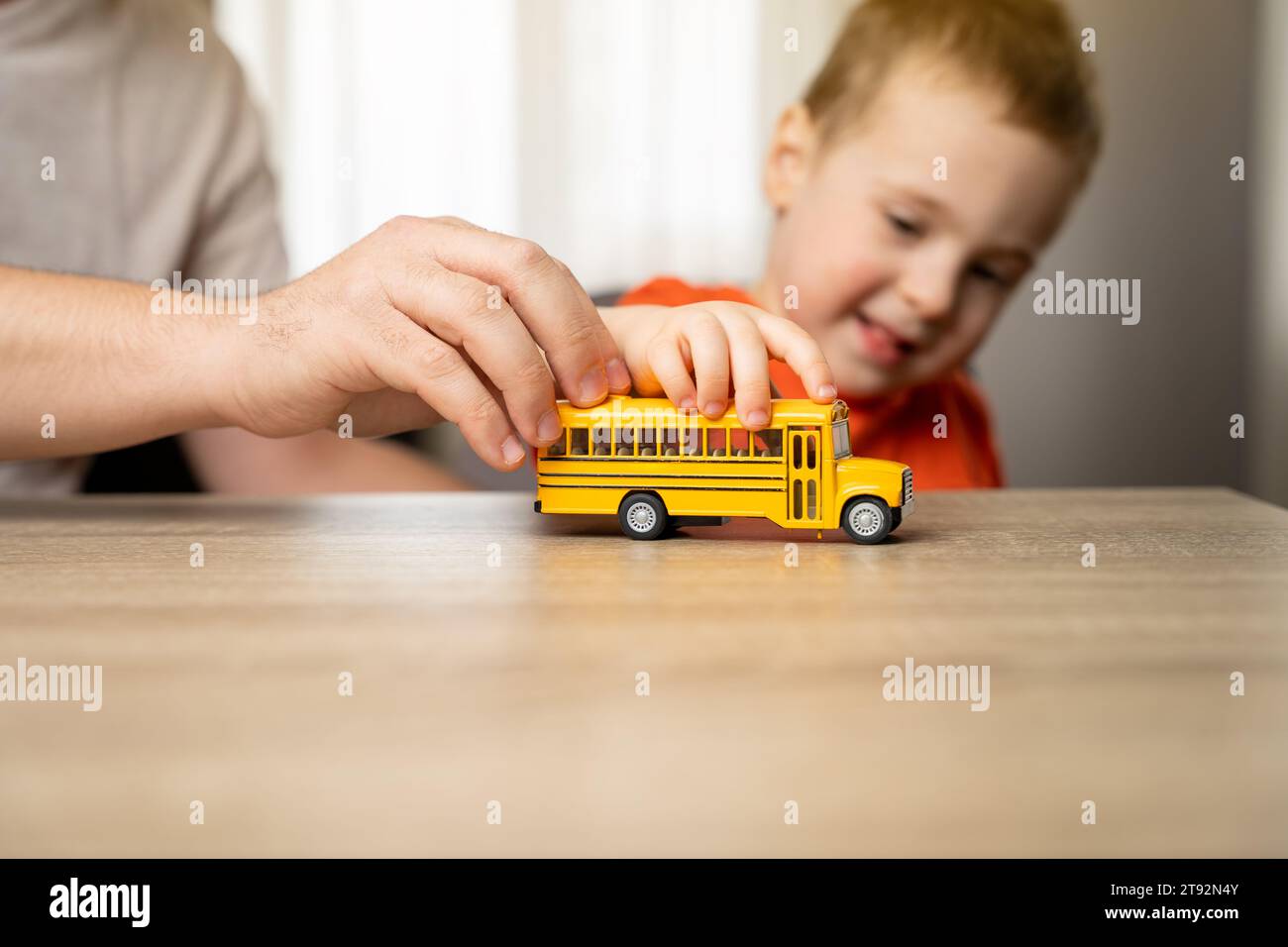 Happy smiling toddler boy playing with yellow car with his dad. Spending time with children. The concept of a happy childhood. Focus on the toy car. Stock Photo