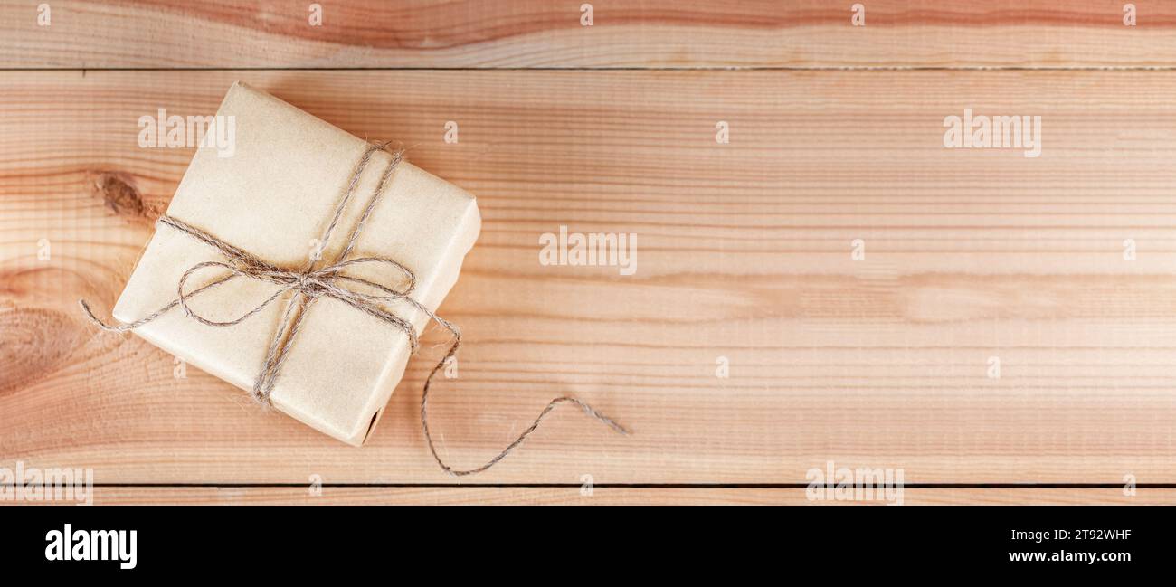 Present box package with congratulation, wrapped brown paper on wooden table. Copy space and holiday concept Stock Photo