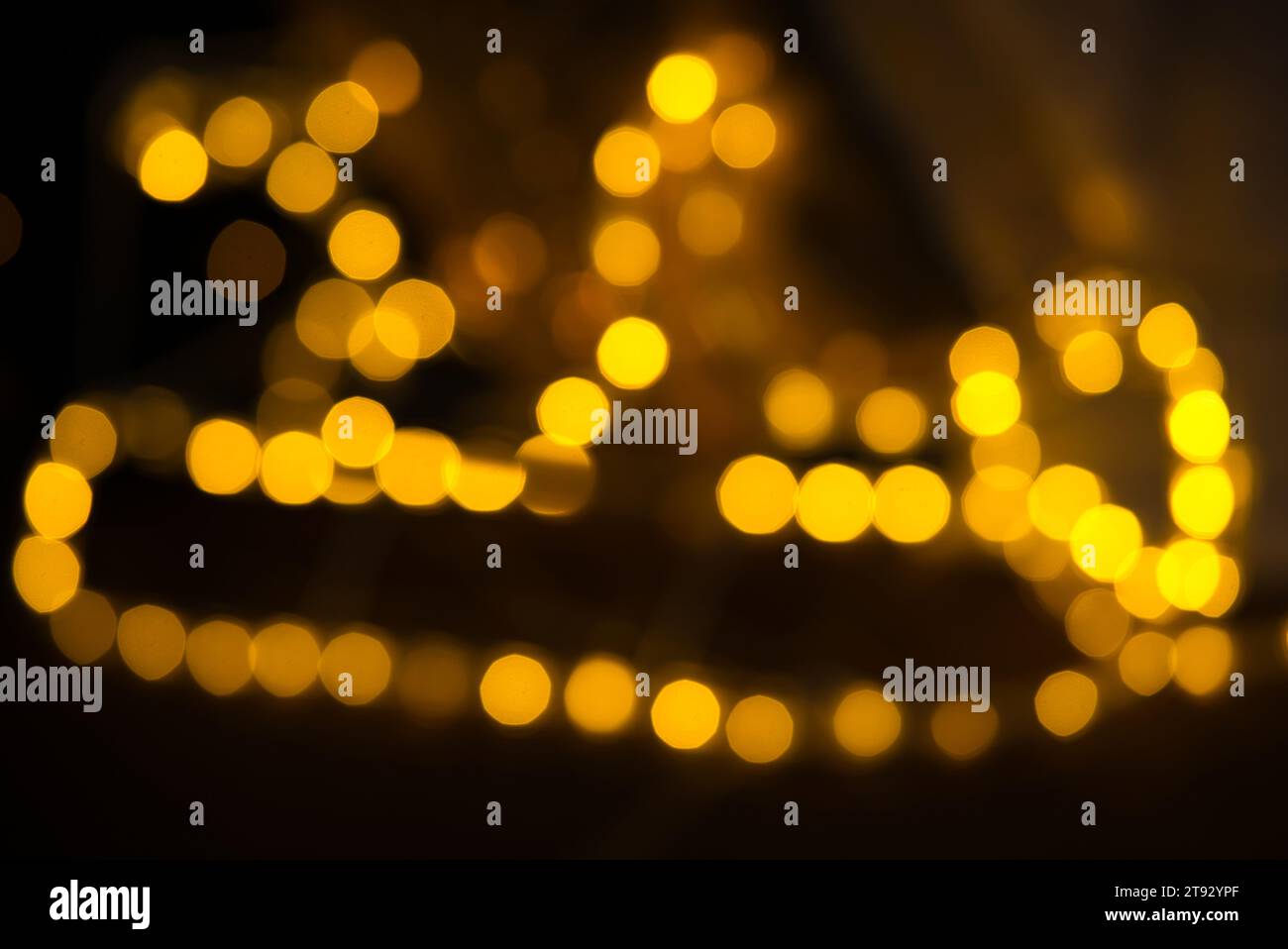 Delight in the festive charm of this bokeh, captured with a 75mm lens, shaping a whimsical sleigh from closely packed glowing ovals and nonagons. The Stock Photo